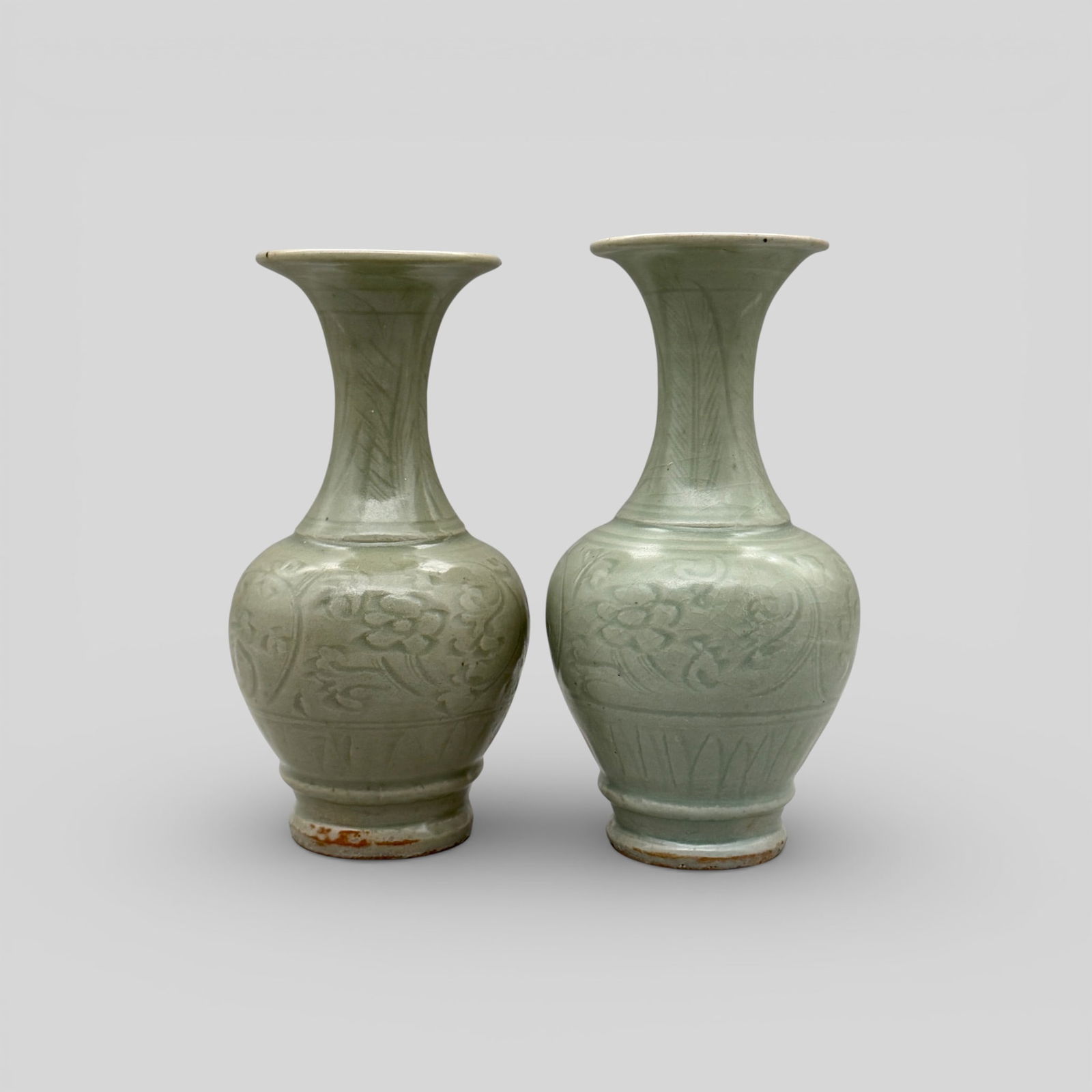 Pair of Longquan Celadon Fluted Vases: Song/Yuan dynasty. A nice pair of vases with flaring lip. Carved decoration to exterior and carved lotus petals to foot. Unglazed foot. Height of each: 8.25" PROVENANCE
