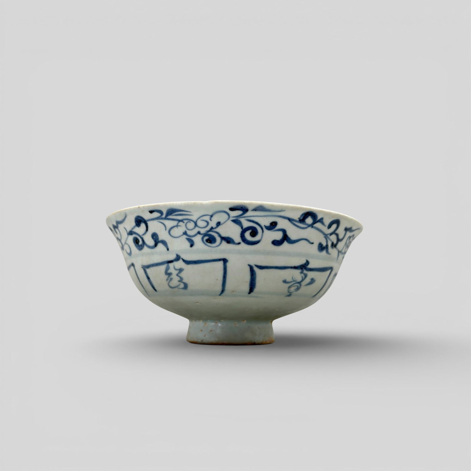 Porcelain Bowl with Underglaze Blue, Yuan: Decorated in grayish blue with a floral scroll and lotus panels on the outside, and a rim band of classic scroll on the inside. At bottom center is a floral design. Diameter: 6.25" PROVENANCE