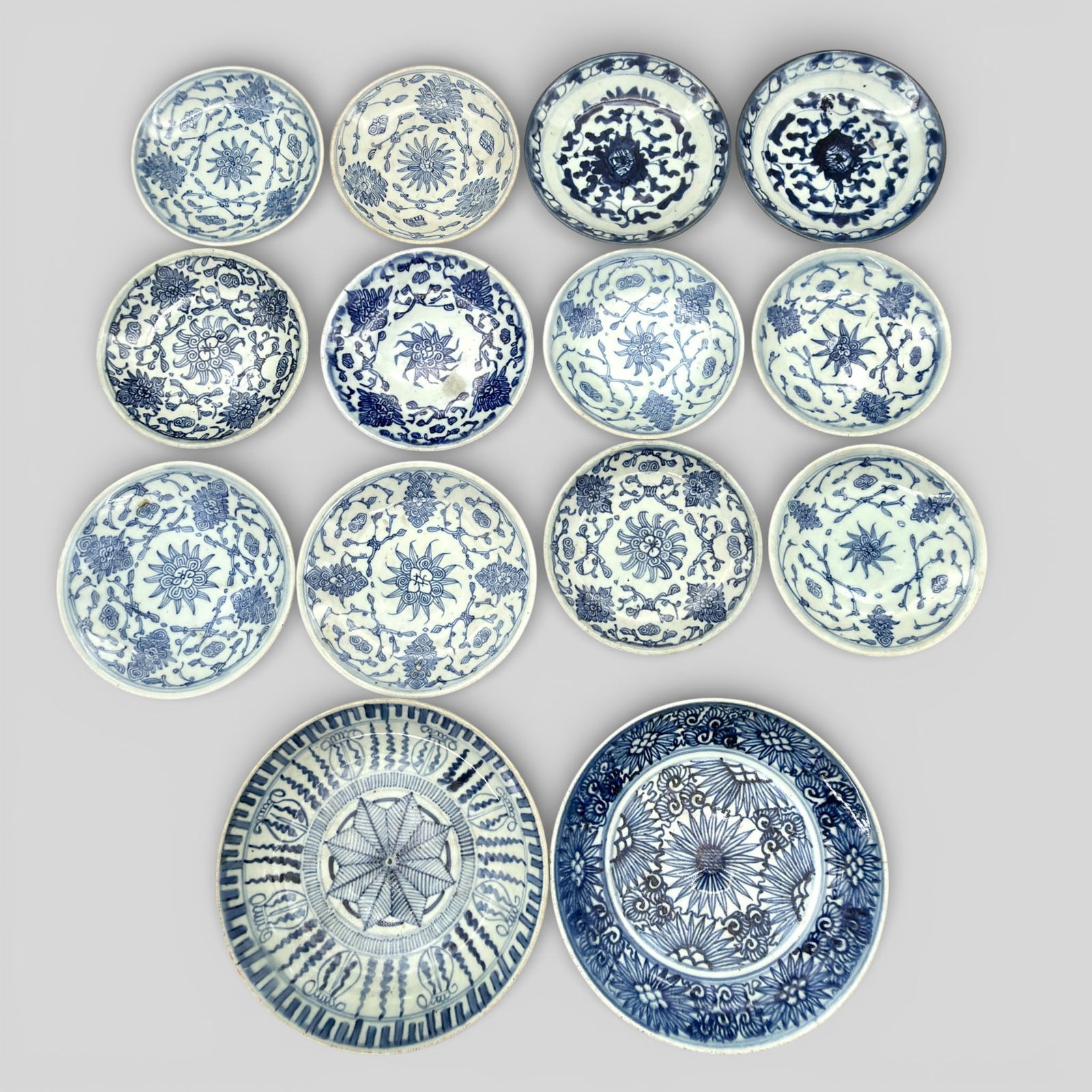 Collection of Late 18th/Early 19th Blue and White Provincial Wares: A collection of 14 dishes, all blue and white and 12 of which contain a similar floral design, each marked the underside and also with old dealer note "Chia Ching". More generally, these are domestic-