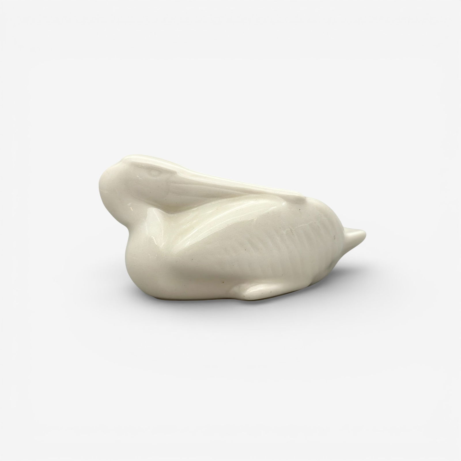 Rookwood Pelican paperweight, glossy white,1932: Rookwood Pelican paperweight in glossy white, a Shirayamadani design, done in 1932. Impressed Rookwood logo, XXXII, shape 6329. Height 2 1/8 inches, length 4 1/2 inches.