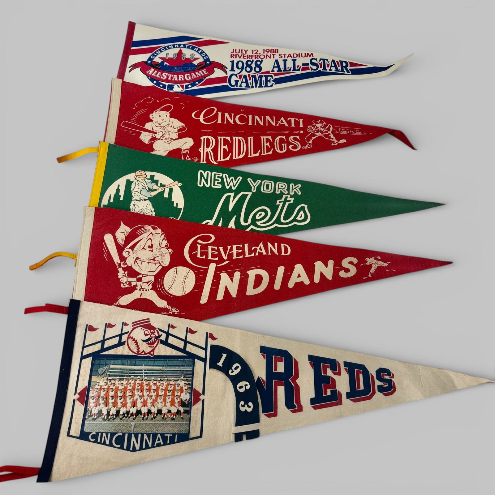 Five Vintage Felt Baseball Pennants - Reds, Mets, Indians: Including three Cincinnati Reds examples, with 1963 team photo pennant and 1988 All-Star Game pennant. Also a Mets and Indians example. Each 29" wd. x 12" at tallest point.