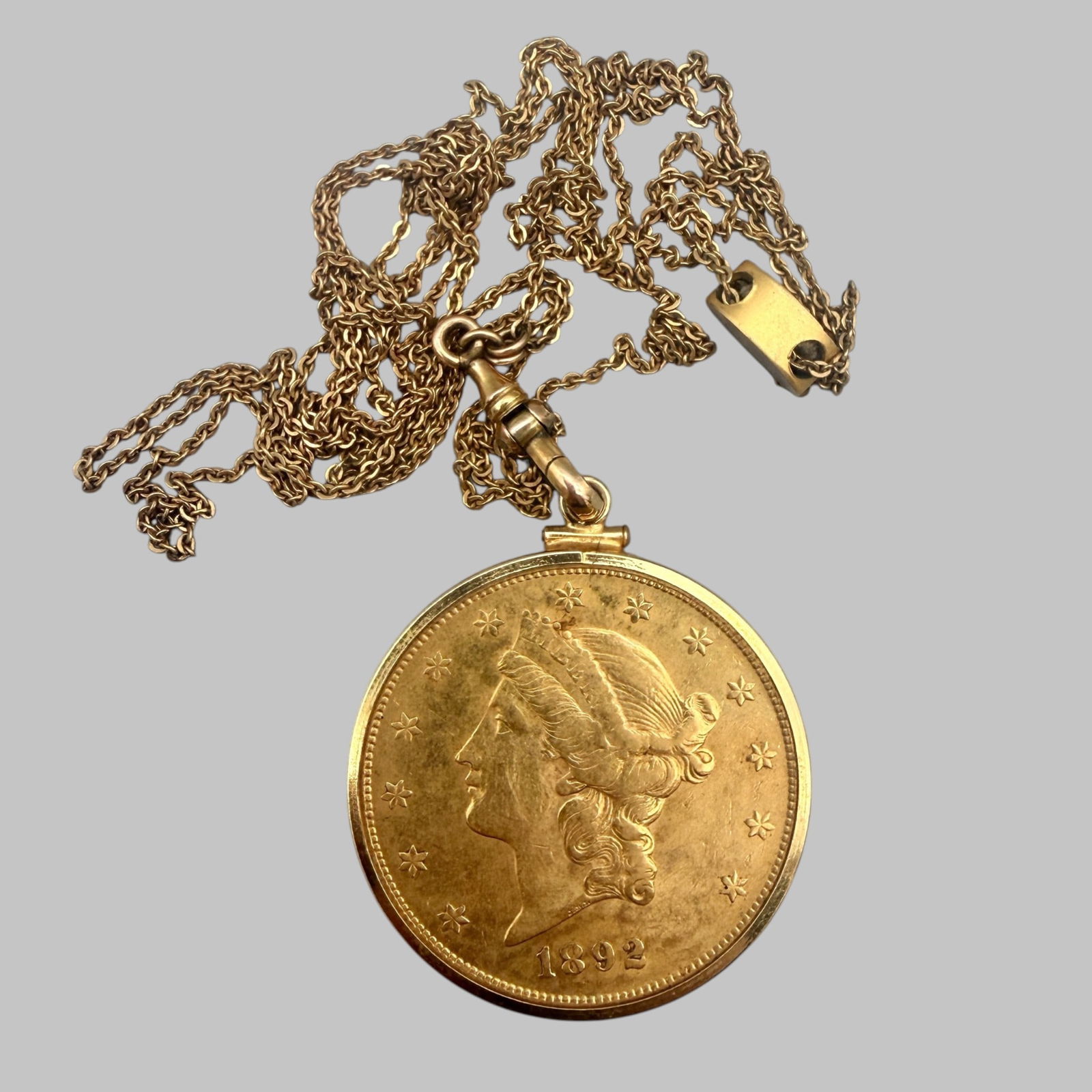 U.S. $20 Coronet Head Gold: 1892-S, mounted in gold bezel with chain; lightly circulated.