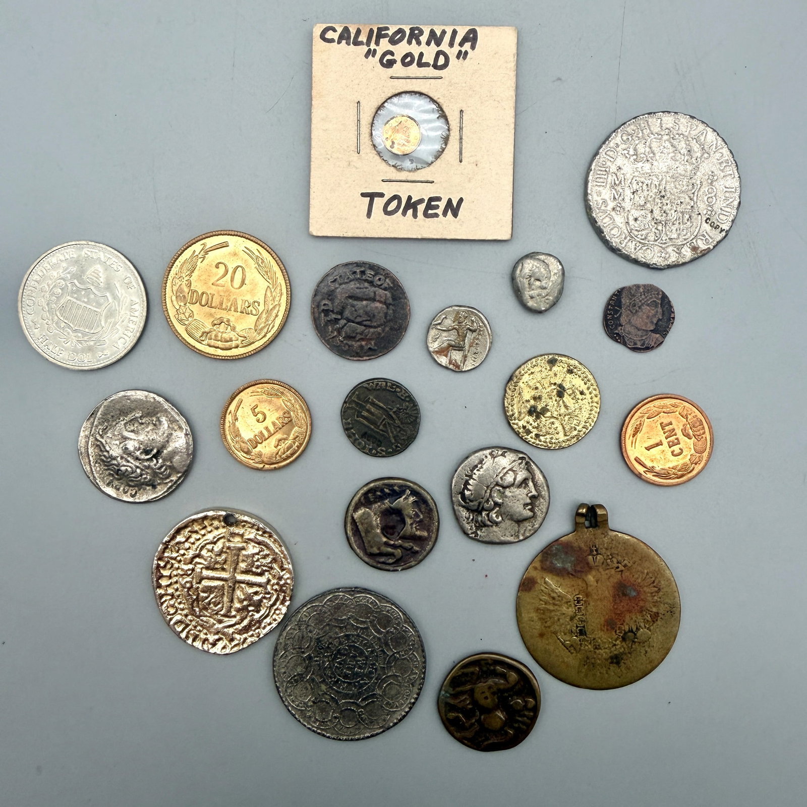 Group of Reproduction Coins: Lot of 19 reproduction pieces including 1776 Continental dollar; 8 reales cob; 1760 Spanish Pillar dollar; Roman & Greek types; CSA denominations; California gold dollar token; Florence Florin; Imperi
