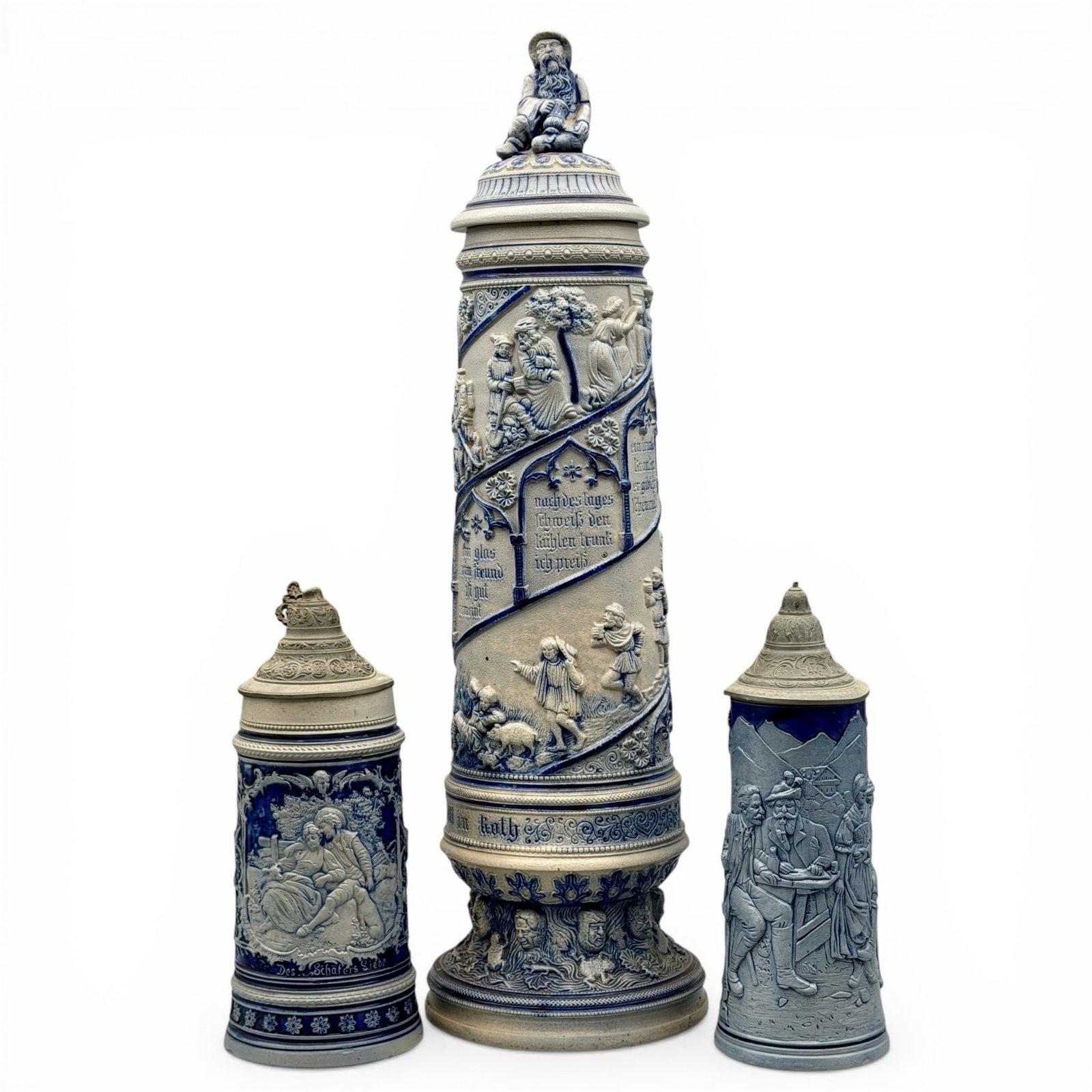 Three Blue and Gray Cobalt Salt Glazed Stoneware Steins: All in nice cobalt blue and gray relief decoration. Tallest height: 23"
