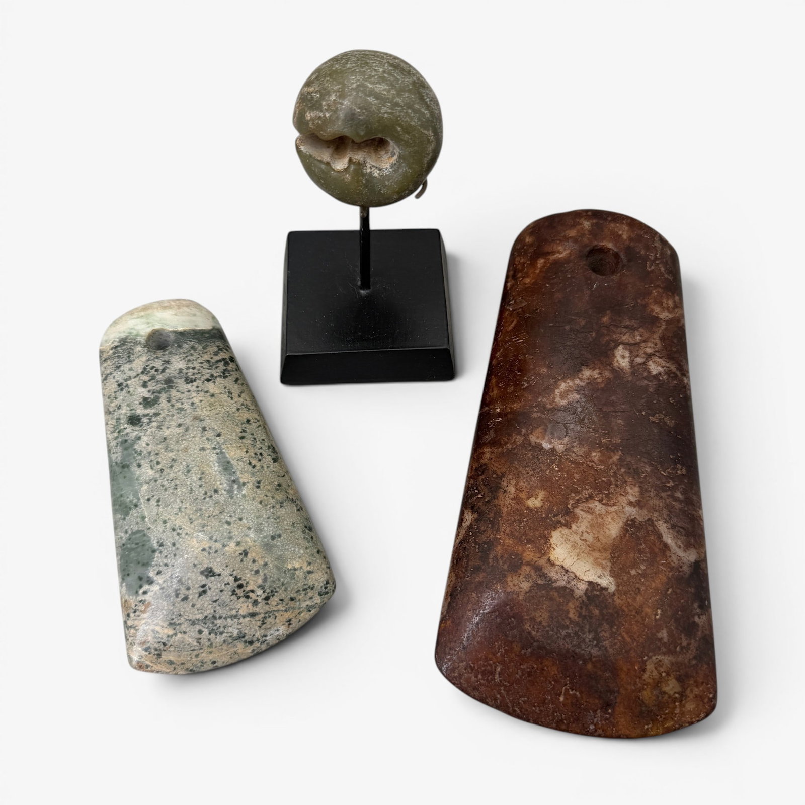 Hongshan Jade Examples: Including three carved examples, one on custom stand, and a pair of axe heads. Tallest ht. 7".