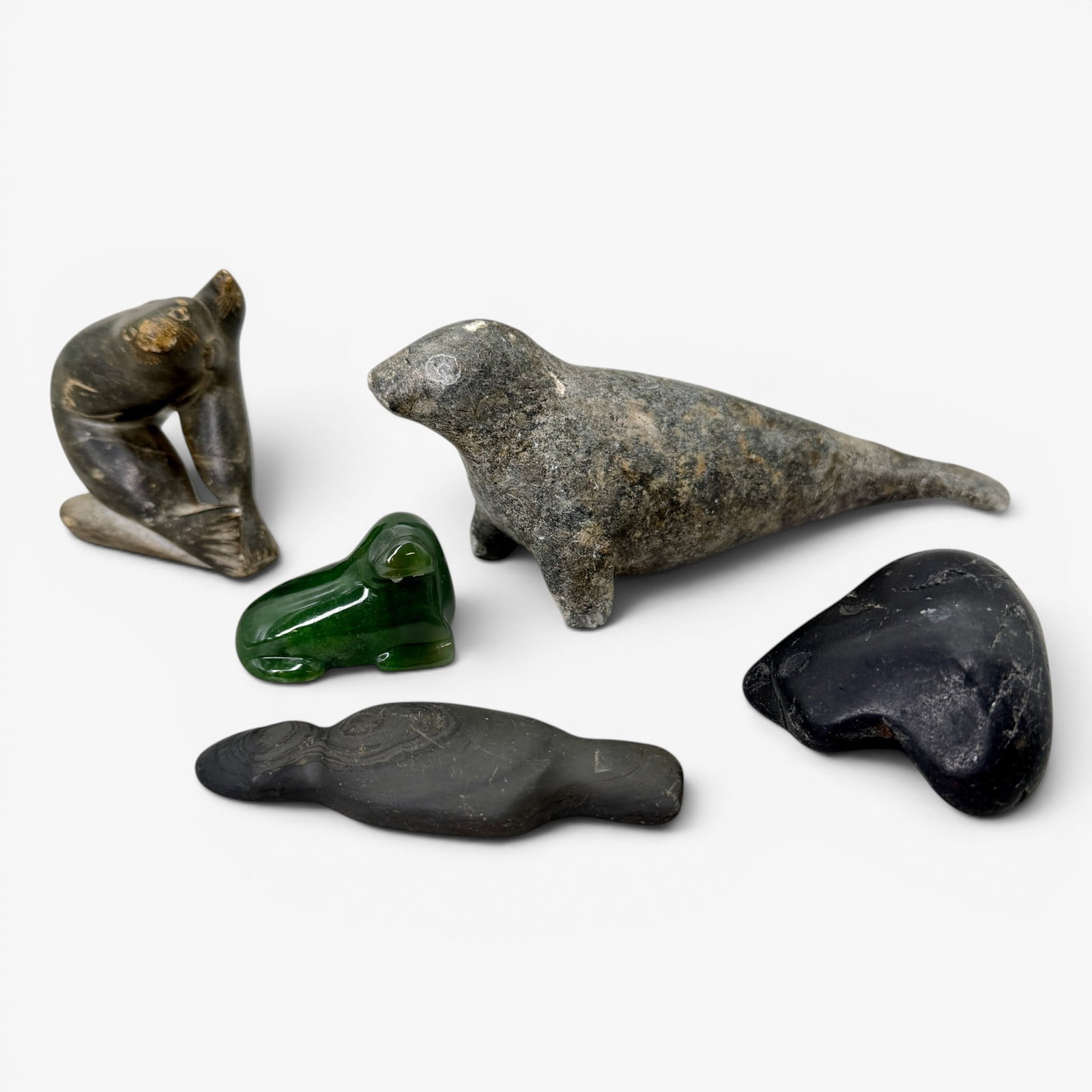 Eskimo Carvings: Four stone and one jade toned, depicting seals and one unfinished work. Longest 7.5".