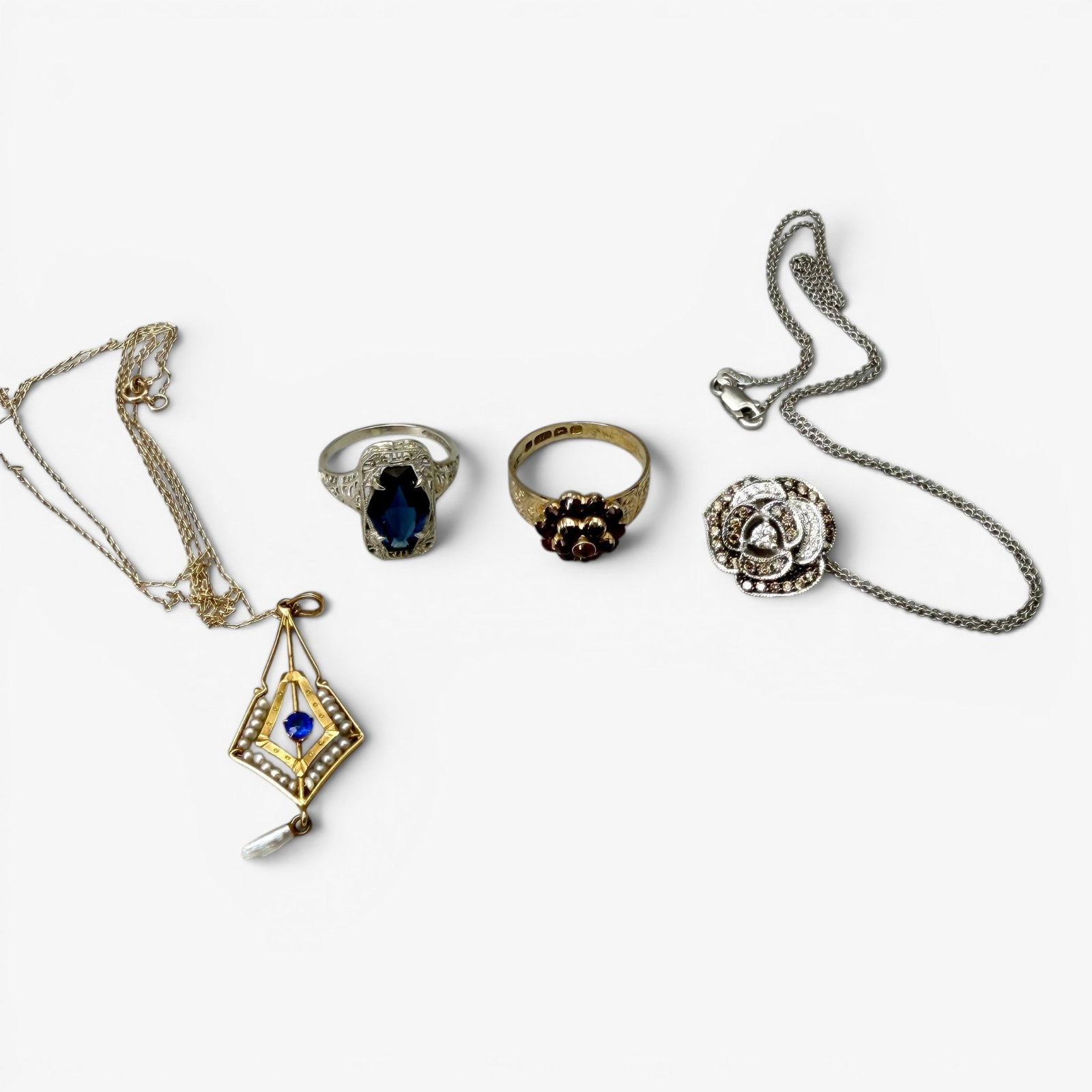 Group of 14K Gold rings/Necklaces: Including one 14k gold ring with inset garnets, one 14k white gold ring with large synthetic sapphire, one 14k gold floral necklace with inset diamonds and lastly a 14k gold necklace with inset seed