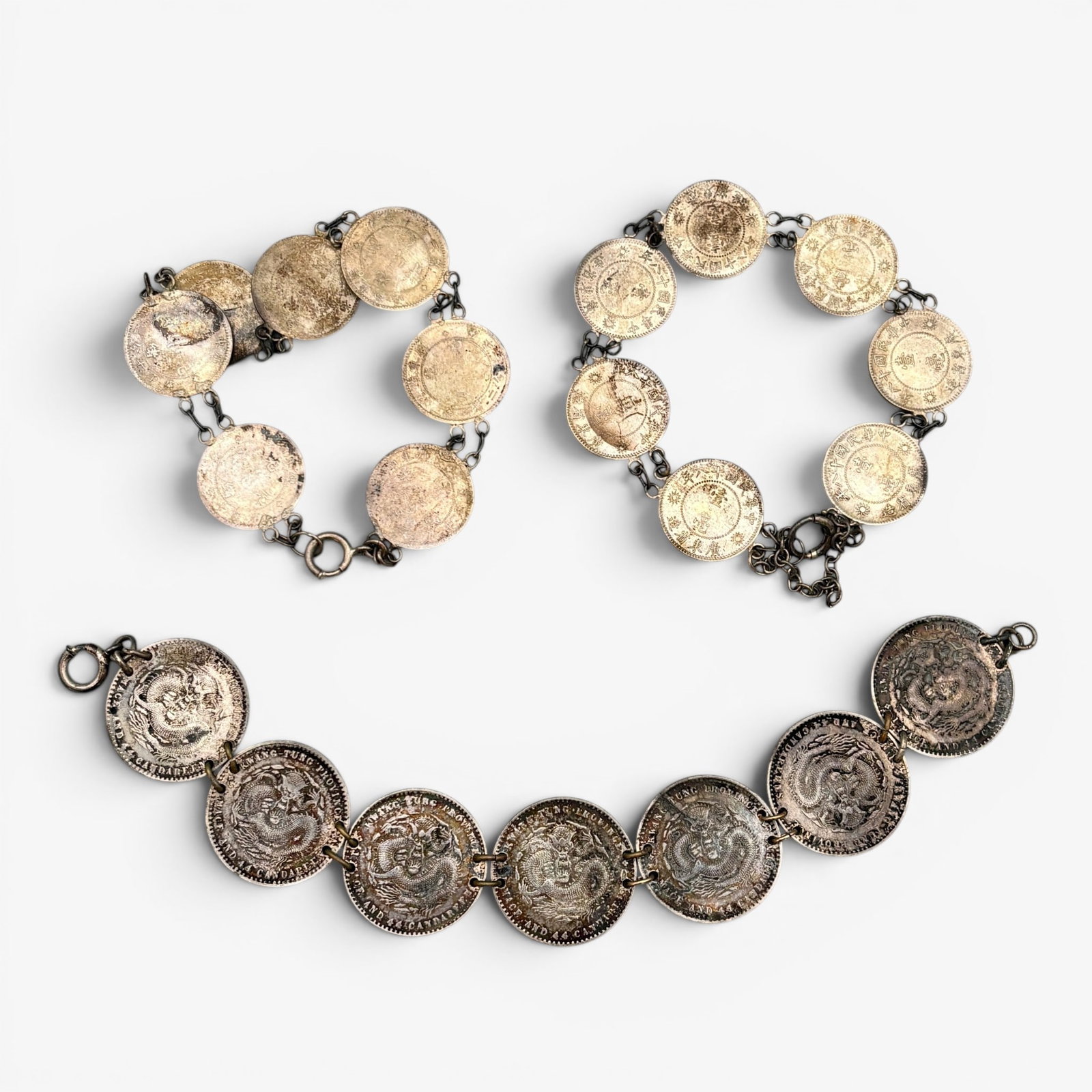 Three Bracelets Constructed of Minted Chinese Coins: Three bracelets in varying lengths that have been combined to create bracelets with clasps. Total weight: 2.55 troy ounces