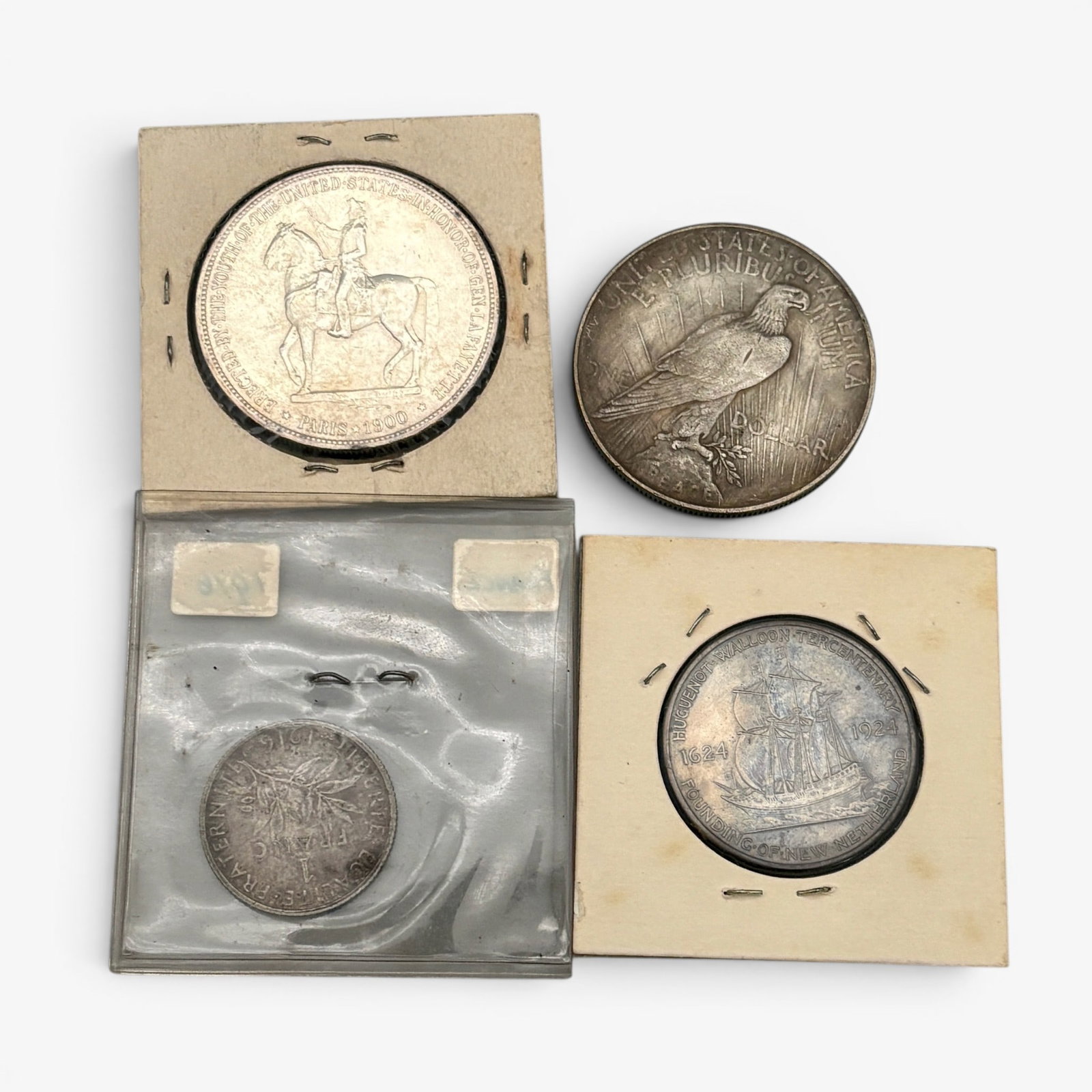 Four Silver Coins, American and French: One 1922 peace dollar, one 1900 Lafayette dollar, one huguenot coin and one 1916 French coin.
