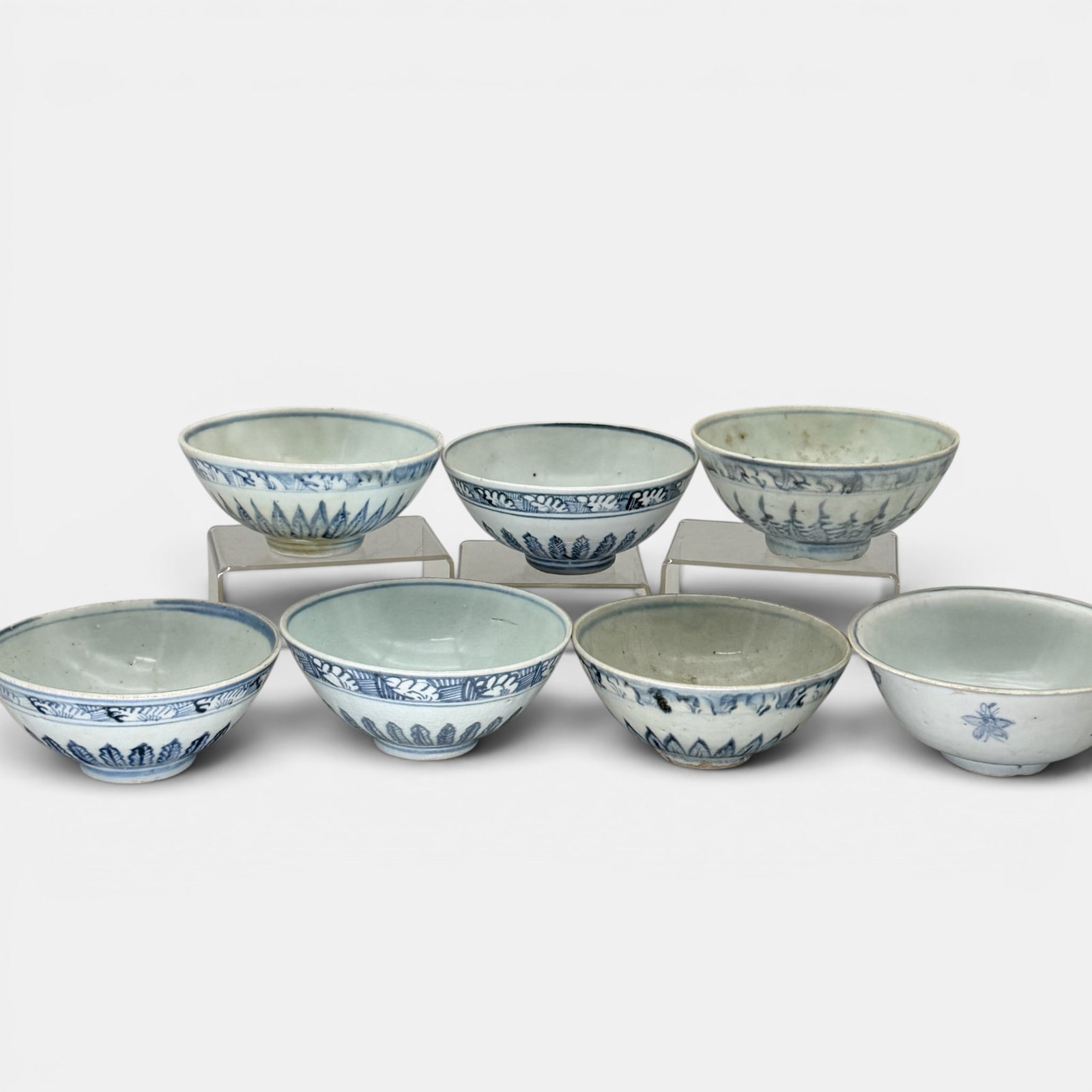 Collection of 7 Ming Blue and White Bowls: Each with similar blue underglazes leaves extending from foot, modest decoration to bodies and bordering rims. Largest ht. 2.5", diameter 6".