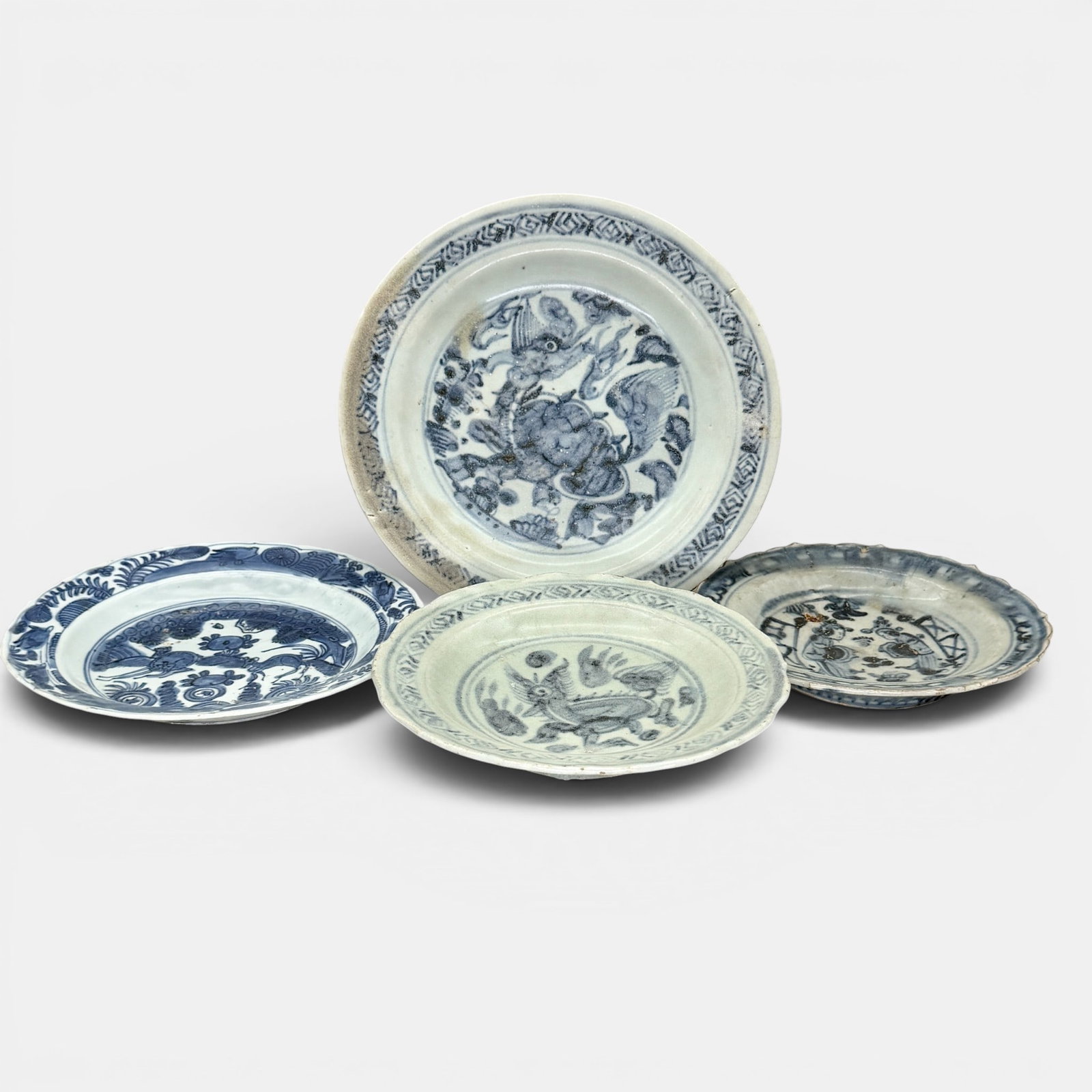 Four Ming Blue and White Plates: One with dragon decoration, the other with deer decoration, one figural scalloped dish and one additional scalloped dish. Largest diameter: 9.5"