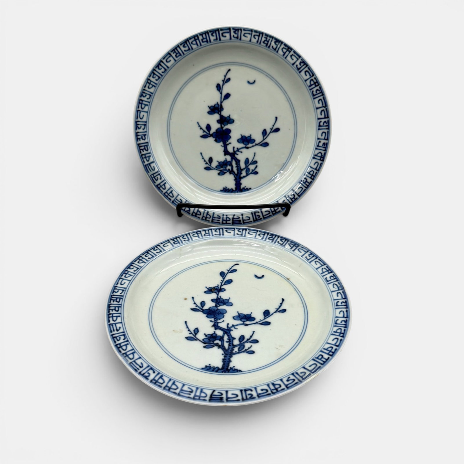 Qing Dynasty Blue and White Decorated Dishes: Both containing the Xuande (later) mark to the underside. 19th century, with foreign calligraphy to the rim. Blooming tree to center of each. Scrolling pattern and florals to exterior bodies. Diameter