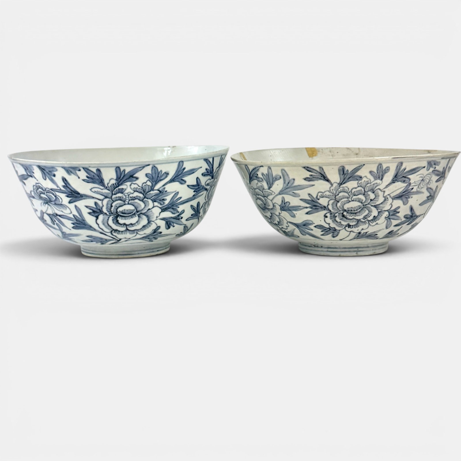 Pair of Very Large Ming Blue and White Bowls: 16th century, a pair of large Ming dynasty bowls with floral design which is very similar, having large floral and leaf design along exterior body. One bowl has significant breaking and cracking along