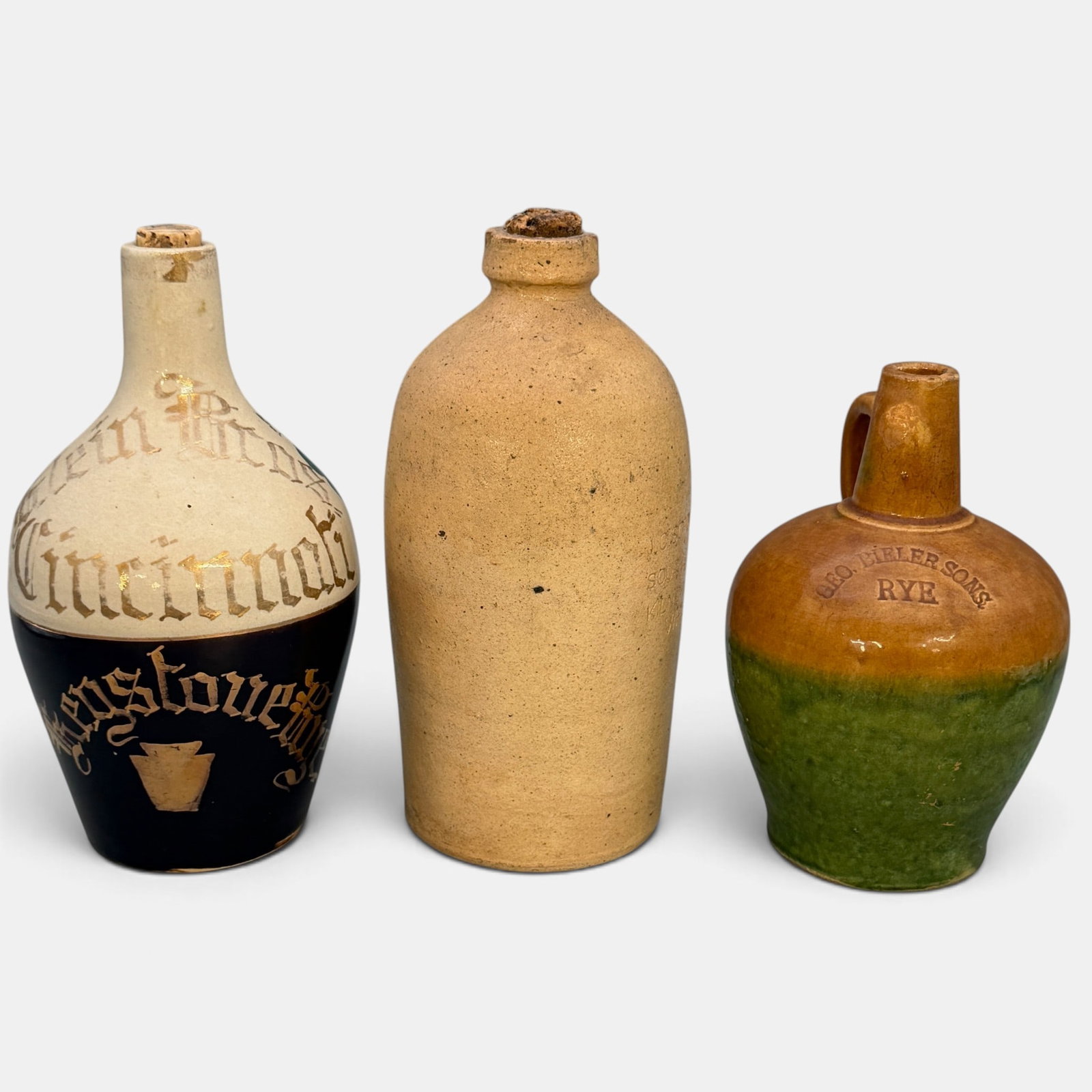 3 Whiskey jugs, all Cincinnati companies: 3 Whiskey jugs, all of Cincinnati origin. 1. Jug impressed "J.C. Schnell's Sour Mash Kiln Dried Grain Whiskey.". Height 8 3/4 inches. 2. Jug impressed "Geo. Bieler Sons Rye' on a two color body. Heigh