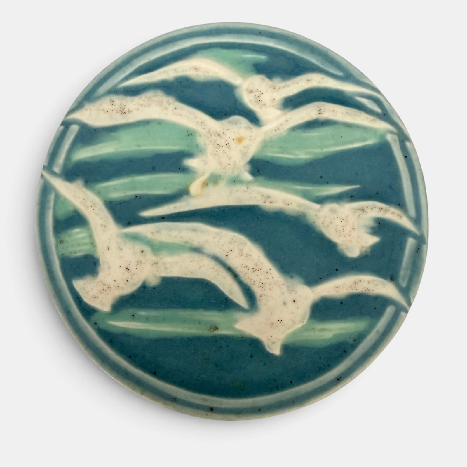 Rookwood Sea Gull trivet, 1918: Rookwood porcelain Sea Gull trivet with five gulls. Impressed Rookwood logo,, XVIII, Shape number 2351, sideways P. Height 7/8 inch, diameter 5 5/8 inches.