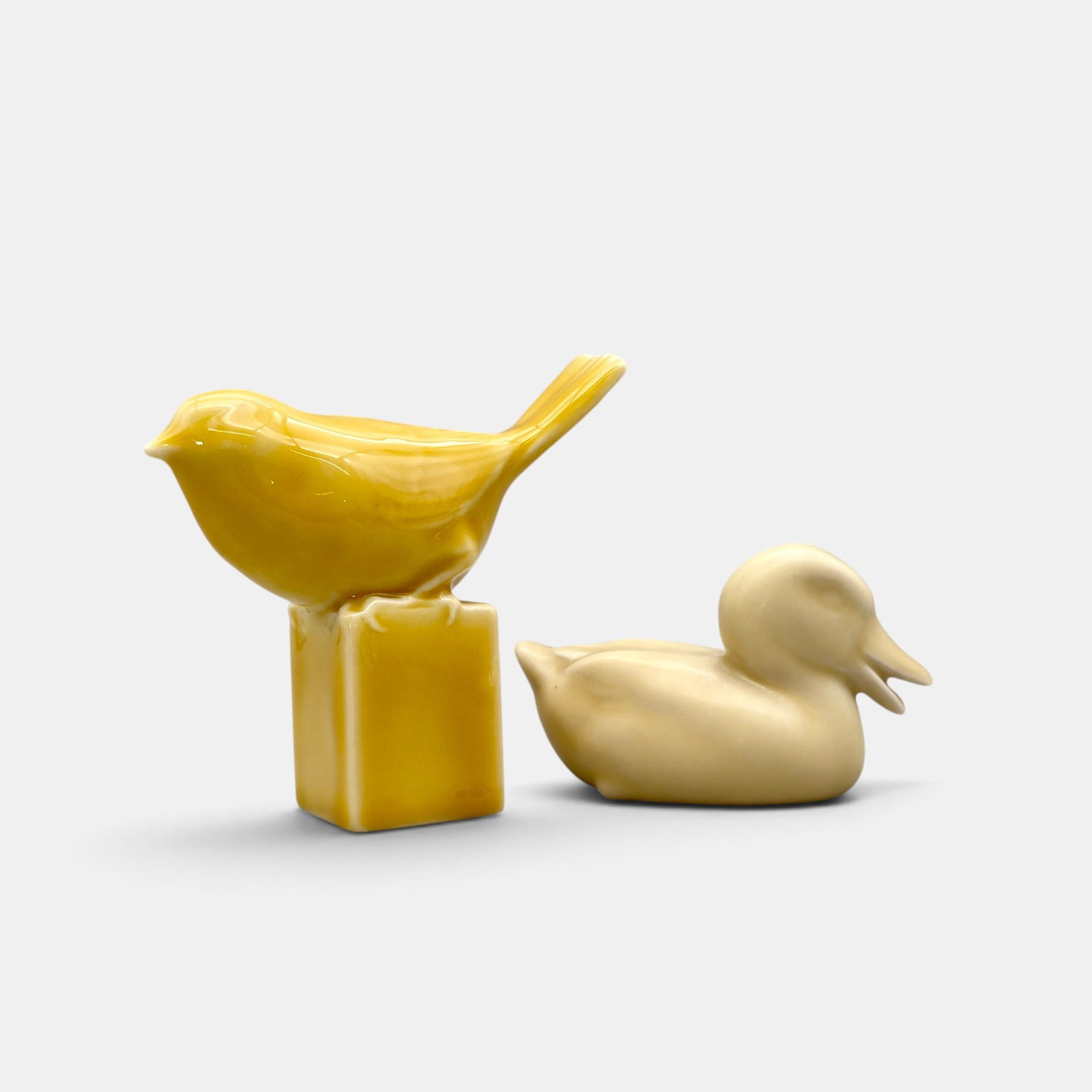 Two Rookwood birds, 1939 Canary and 1929 Duck: Two Rookwood bird paperweights, a 1939 Canary in yellow and a 1929 Duck in white. Impresseed Rookwood logo and shape numbers 6383 and 6064. Height of tallest, 3 7/8 inches.