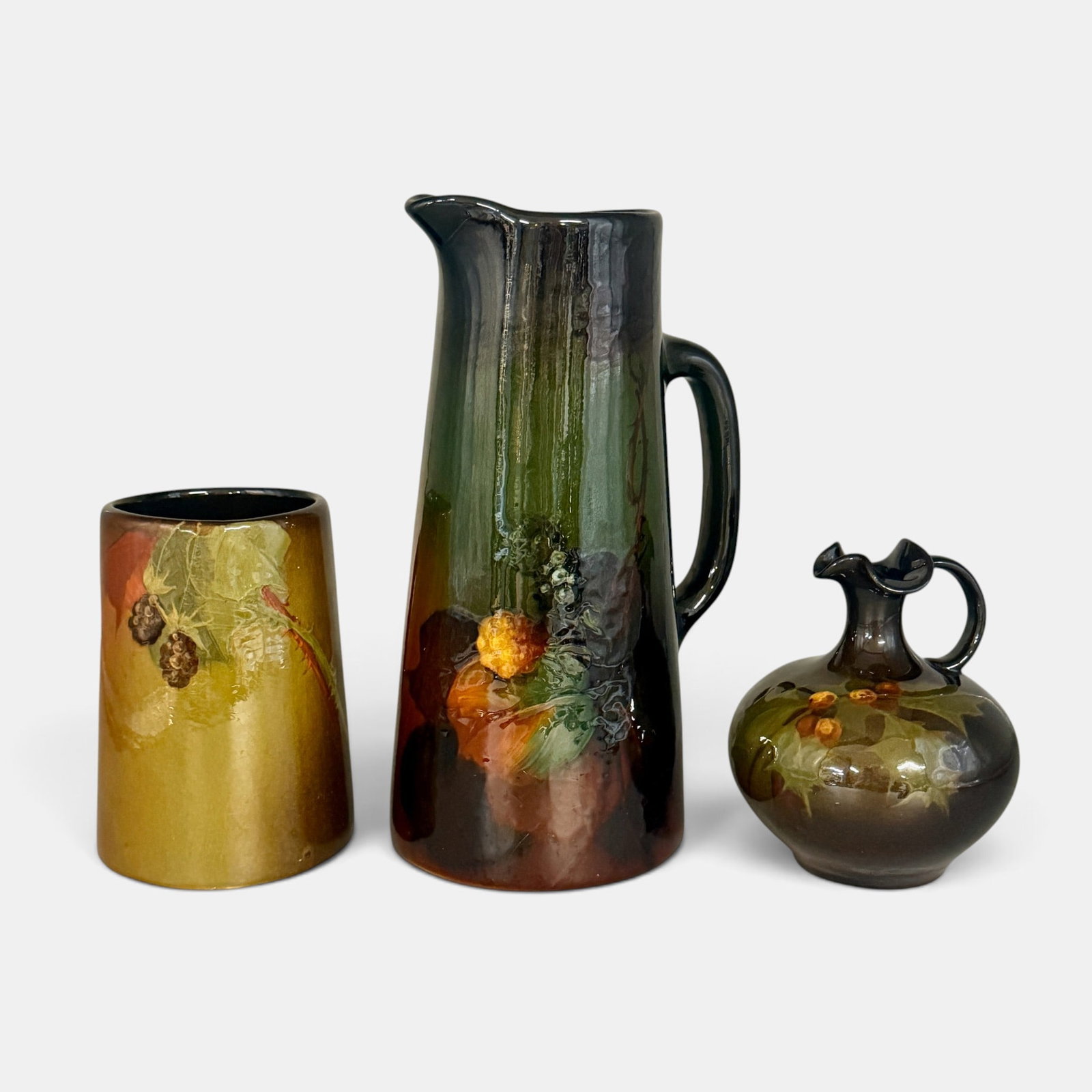 Three Weller Louwelsa items: Three Weller Louwelsa items. 1. Mug with blackberries. 2. Tankard also with blackberries. 3. Ewer with holly berries and leaves. Tallest 11 7/8 inches. No artist's signatures but all with Weller