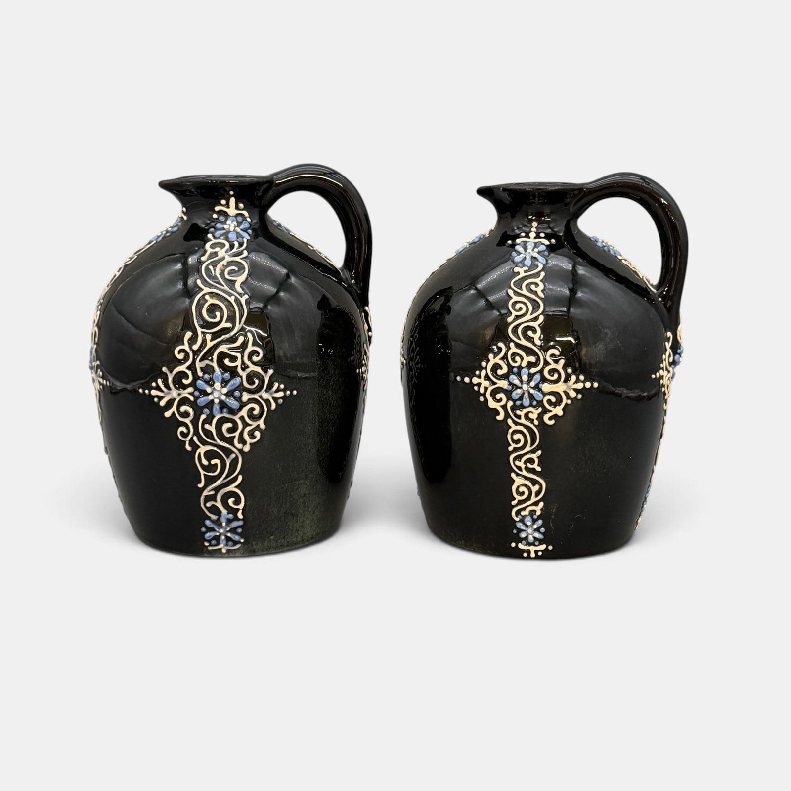 Two Weller Turada jugs, blue and white slip: Two Weller Turada jugs having blue and white slip on a black ground. Neither are marked. Height of rach is 7 1/8 inches.