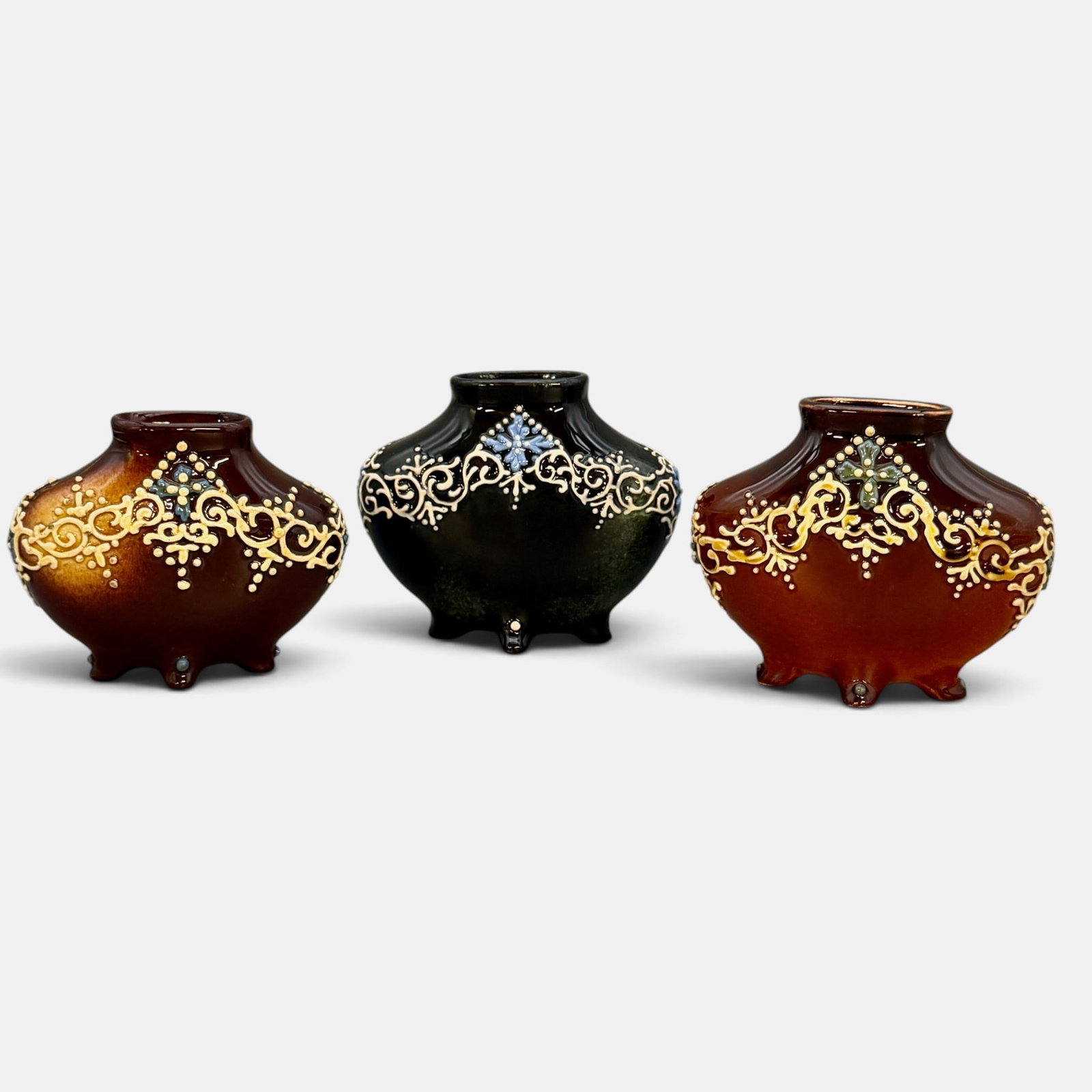 Three Weller Turada oval vases on four feet: Three Weller Turada oval vases, each with four feet, two with brown backgroud and one with near black background. None are marked. Heght of each 4 1/4 inches.