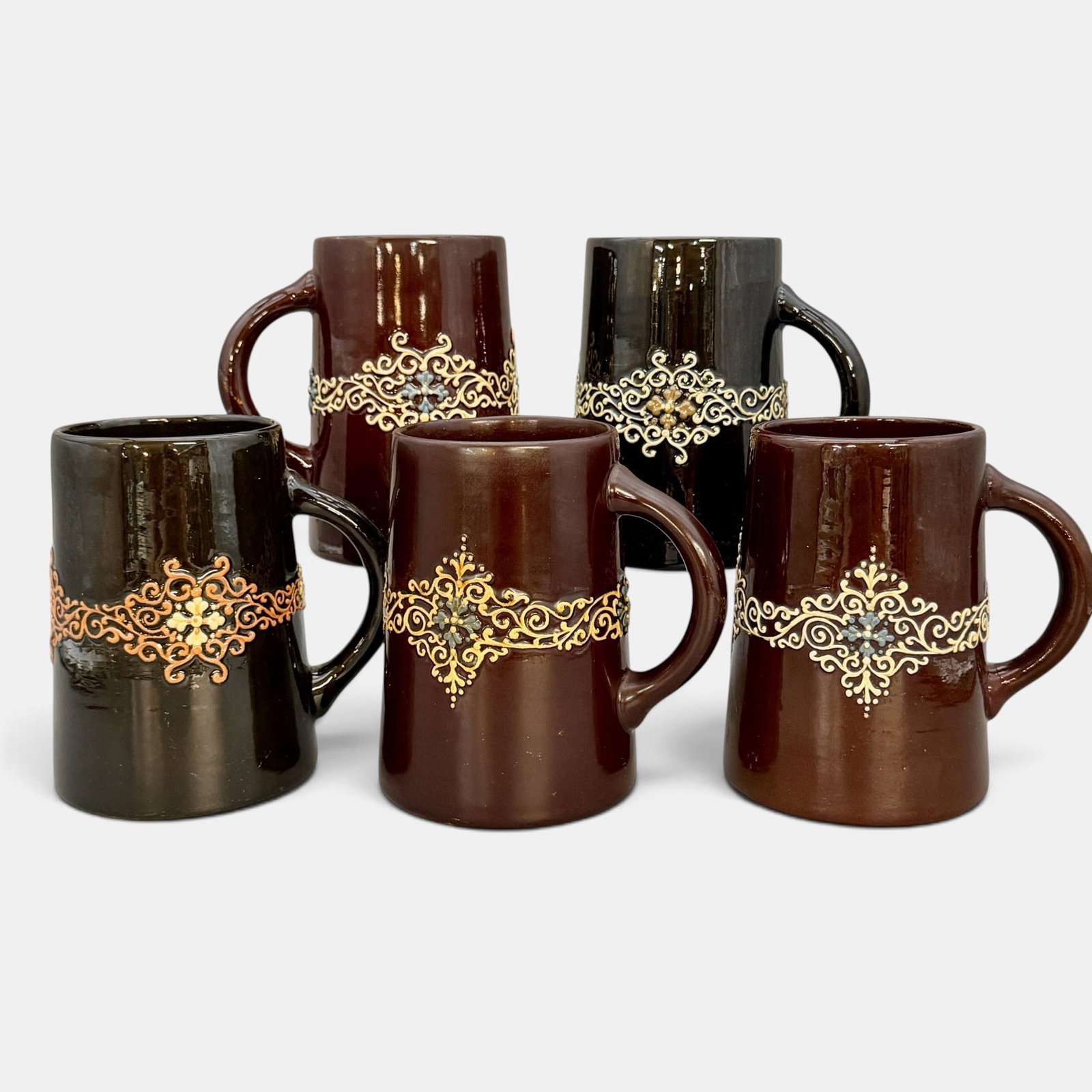Five Weller Turada mugs: Five Weller Turada mugs, each with slightly different colors on a dark brown background. All impressed Turada Weller 562. Height of each 5 3/4 inches.