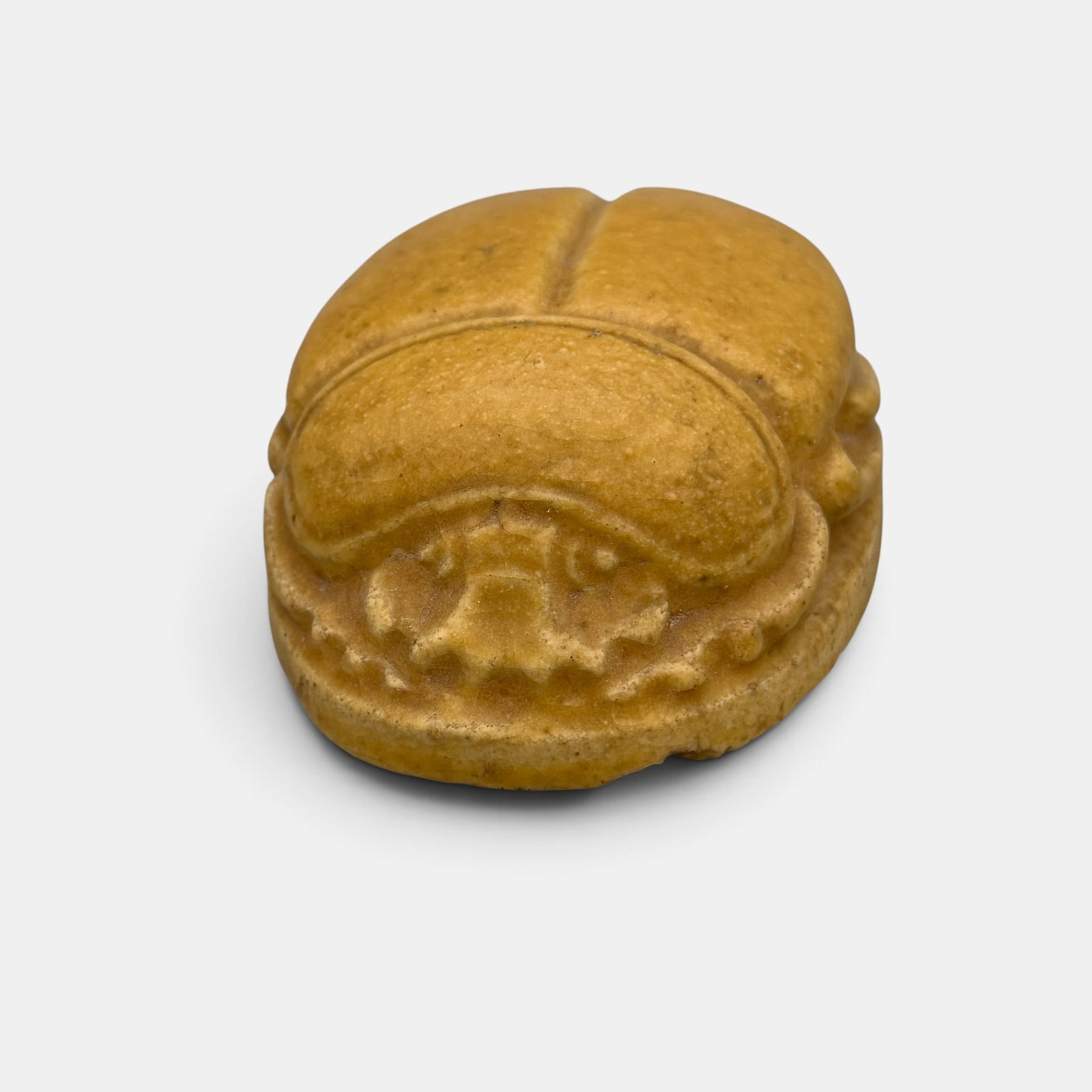Grueby Faiece Scarab paperweight, tan mat: Grueby Faience Scarab paperweight in tan mat. Impressed Grueby Faience circular logo. Height 1 3/8 inches, length 3 7/8 inches.