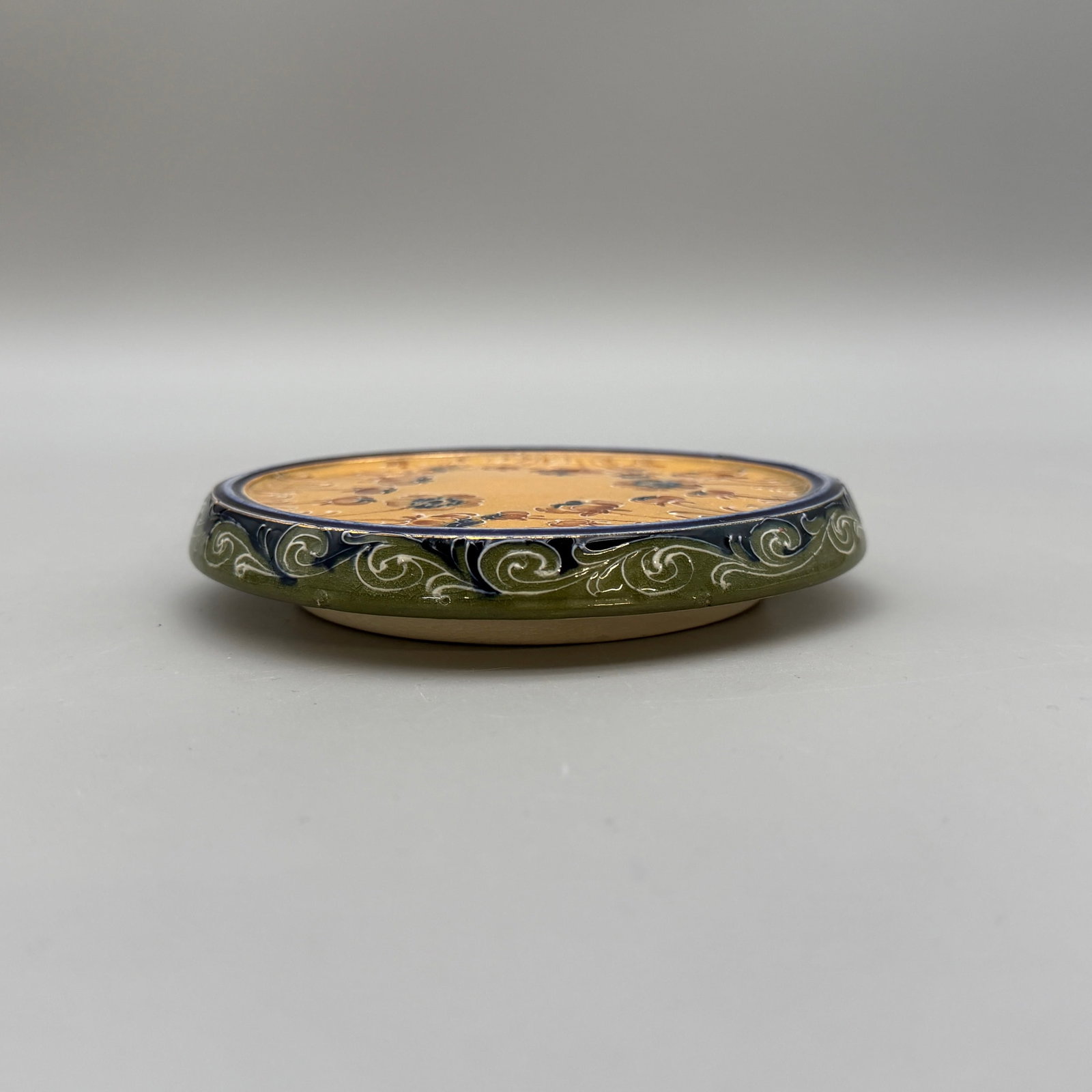 MacIntyre-Moorcroft tea tile, poppy design: MacIntyre-Moorcroft tea tile in poppy design. MacIntyre Burslem ink stamp logo. Painted in red slip M 1757. Height 7/8 inch. Diameter 5 1/4 inches.