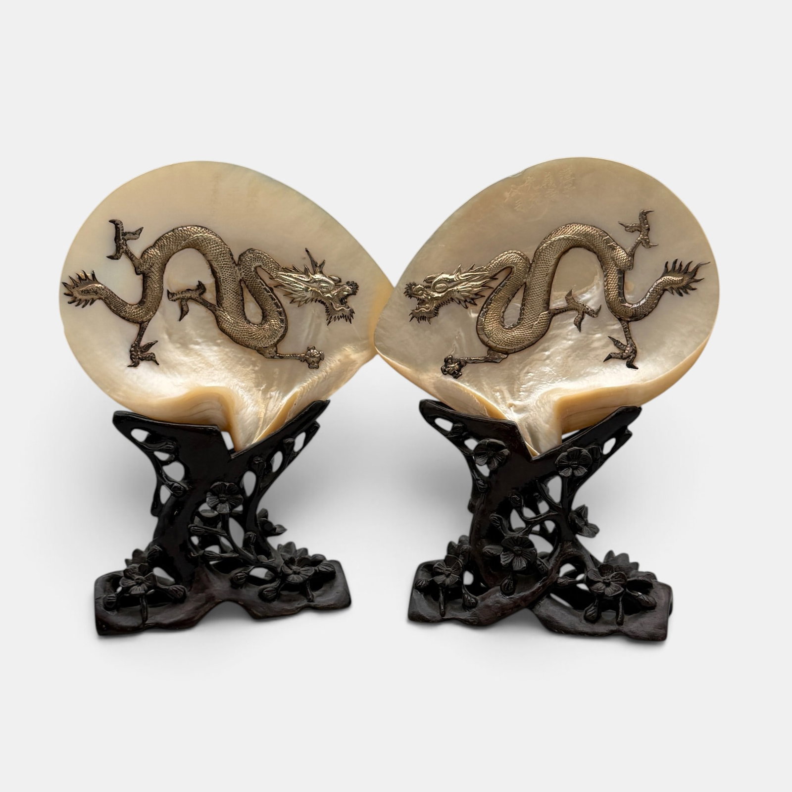 Pair of Inlaid Chinese MOP Shells: A dated (1917) pair of MOP shells with dragons bolted in, each with incised inscriptipon dating them, atop rosewood stands. Ht. of each 11".