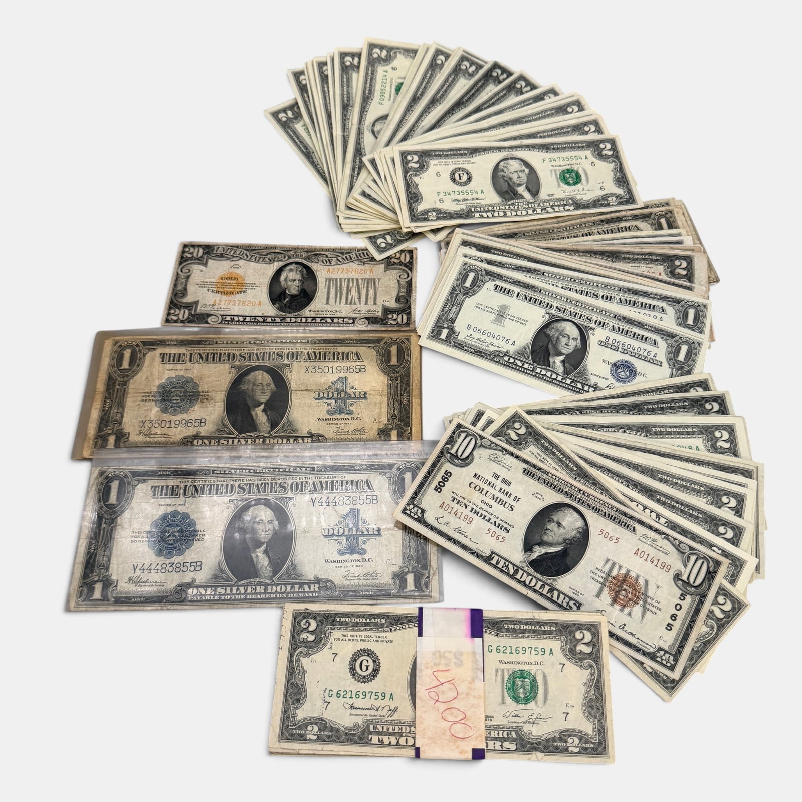 Variety of Currency, Including 2$, 20$ Gold Cert., and $1: A large grouping of 2$ bills, 1$ bills, blue and red seal, as well as one 20$ Jackson gold certificate, and 2 Washington silver certificates.