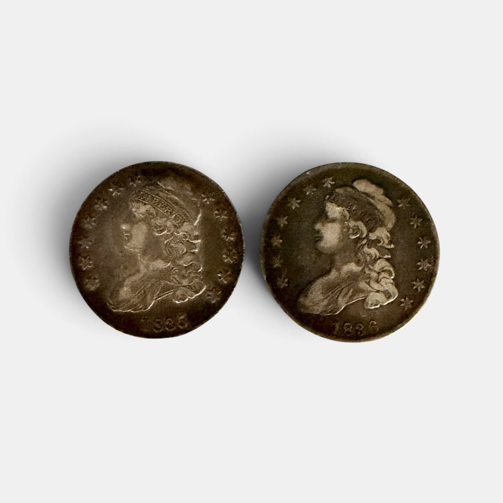Pair of Capped Bust Half Dollars, 1835 and 1836: One being heavily worn and circulated and the other presenting much less worn.