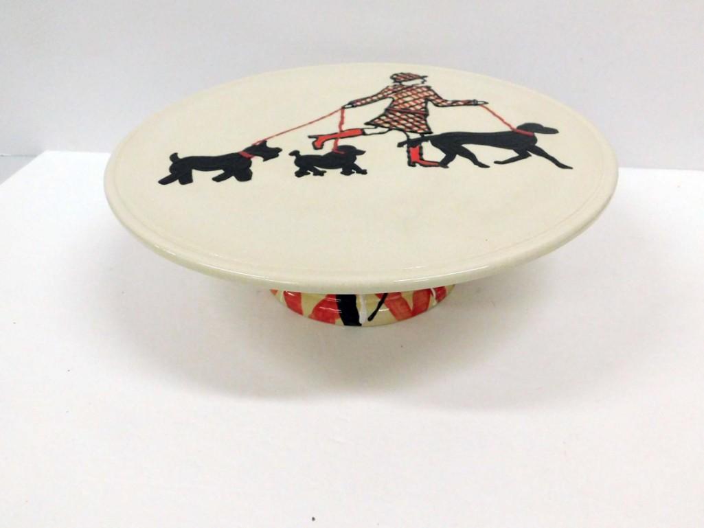 Cake Stand w Lady in Boots Walking Dogs: Cake Stand w Lady in Boots Walking a Scottie or Schnauzer Dog, a Poodle, and another dog, approx 12" in diameter and 4" tall . Handmade , Signed , and Dated