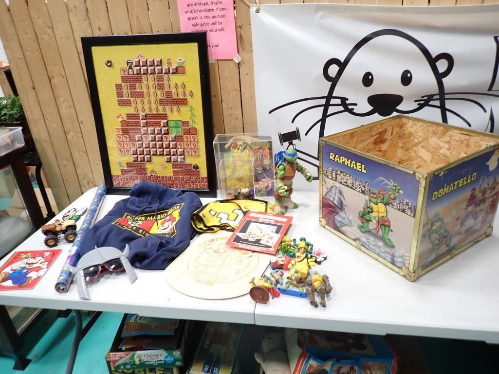 Lot of Super Mario & TNMT Teenage Mutant Ninja Turtles Collectibles: Lot of Super Mario & TNMT Teenage Mutant Ninja Turtles Collectibles including a vintage TMNT chest (no lid), artwork signed, toys, Mario Pizza paddle, hoodie, toys, book, framed puzzle
