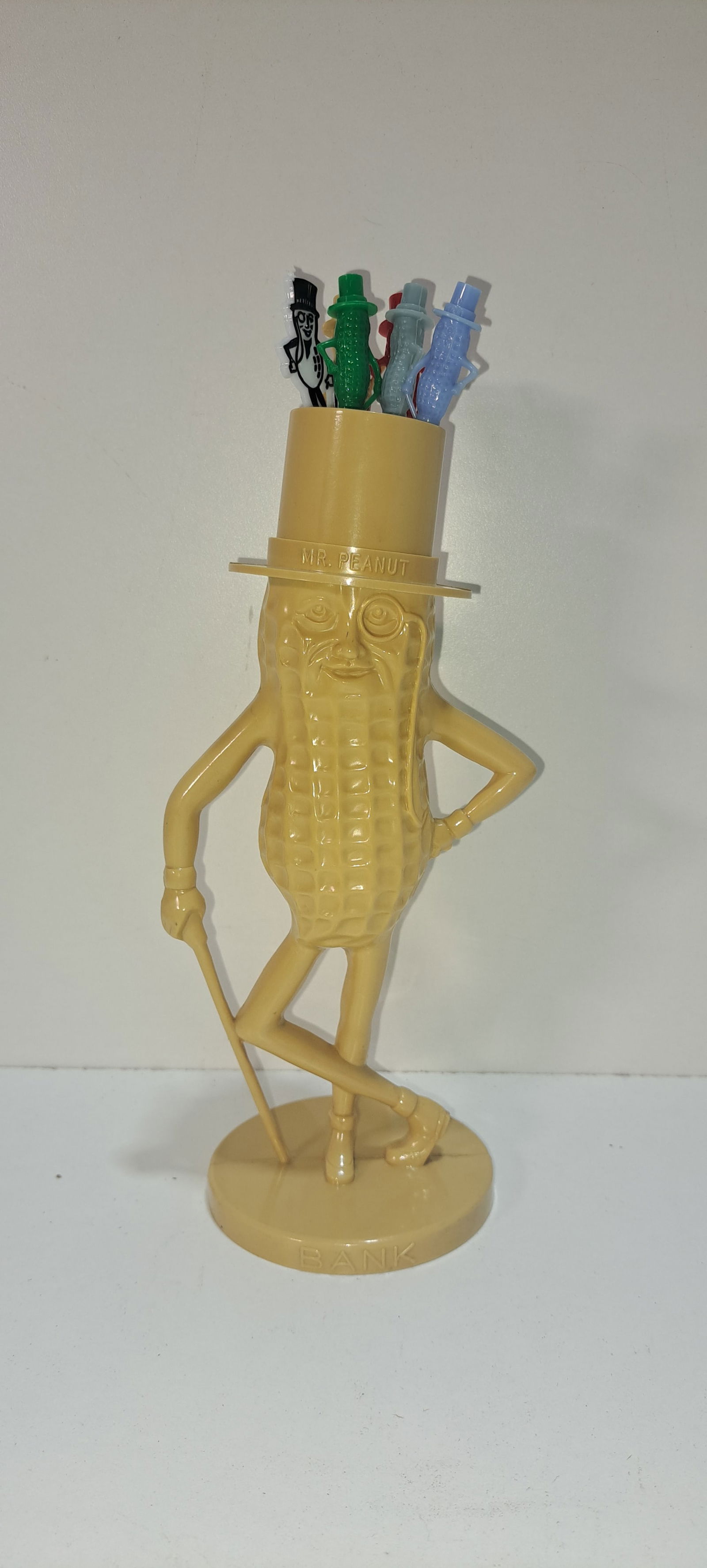 tan Mr. Peanut stirrer holder: tan, plastic, figural, Mr. Peanut stirrer holder, with 6 different stirrers, small crack on rear hat brim as shown. Otherwise good condition, approx. 8.5" tall, Please note: if picking up, location