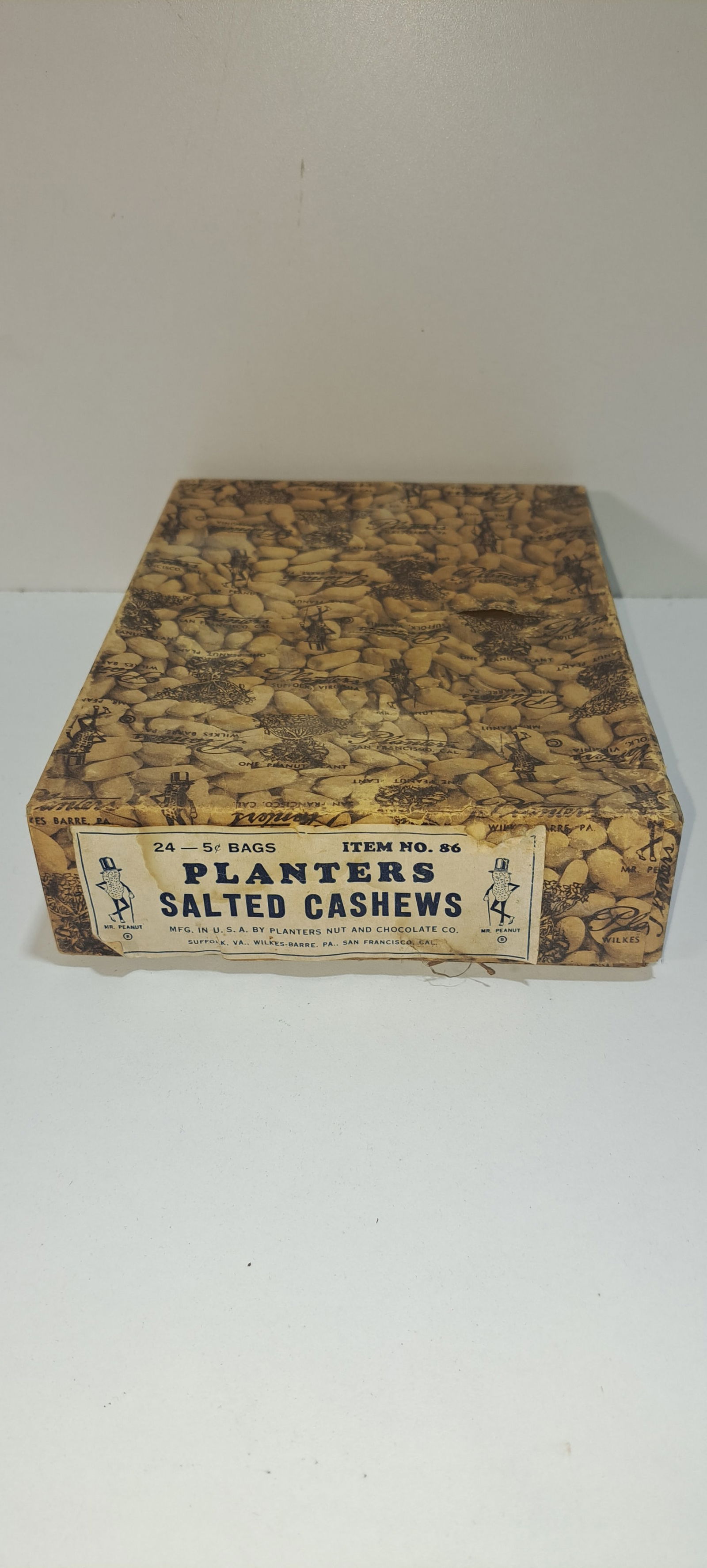 Planters Peanuts cardboard box: Planters Peanuts cardboard box with lid, held 24- 5cent bags of salted cashews, has label, wrapped in paper with peanuts, peanut plants and numerous Mr. Peanuts, small tear in paper, overall minor wea