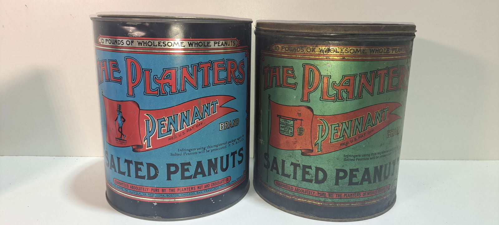 (2) Planters Peanuts tins: 2 different Planters Peanuts, 10 lb. Pennant Brand tins, both with correct lids, each show some wear, each approx. 8.5" diameter, 9.75" tall, Please note: if picking up, location is different than auc