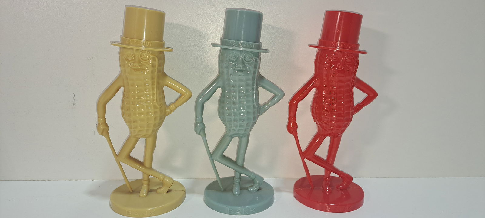 (3) Mr. Peanut banks: 3 plastic, figural, Mr. Peanut coin banks, tan, blue, red, red bank has small chip on base, others in good condition, each approx. 8.5" tall, Please note: if picking up, location is different than