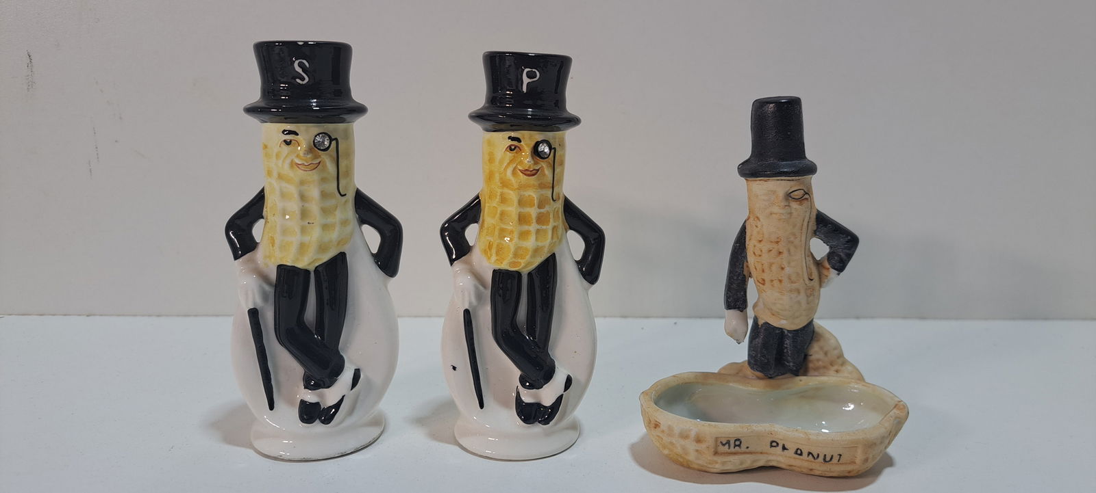 Mr. Peanut ceramic lot: Mr. Peanut ceramic salt and pepper set with rhinestones in monocles, tiny chip on hat of salt shaker, otherwise good condition, approx. 4.5" tall, ceramic Mr. Peanut ashtray, missing wire cane, otherw
