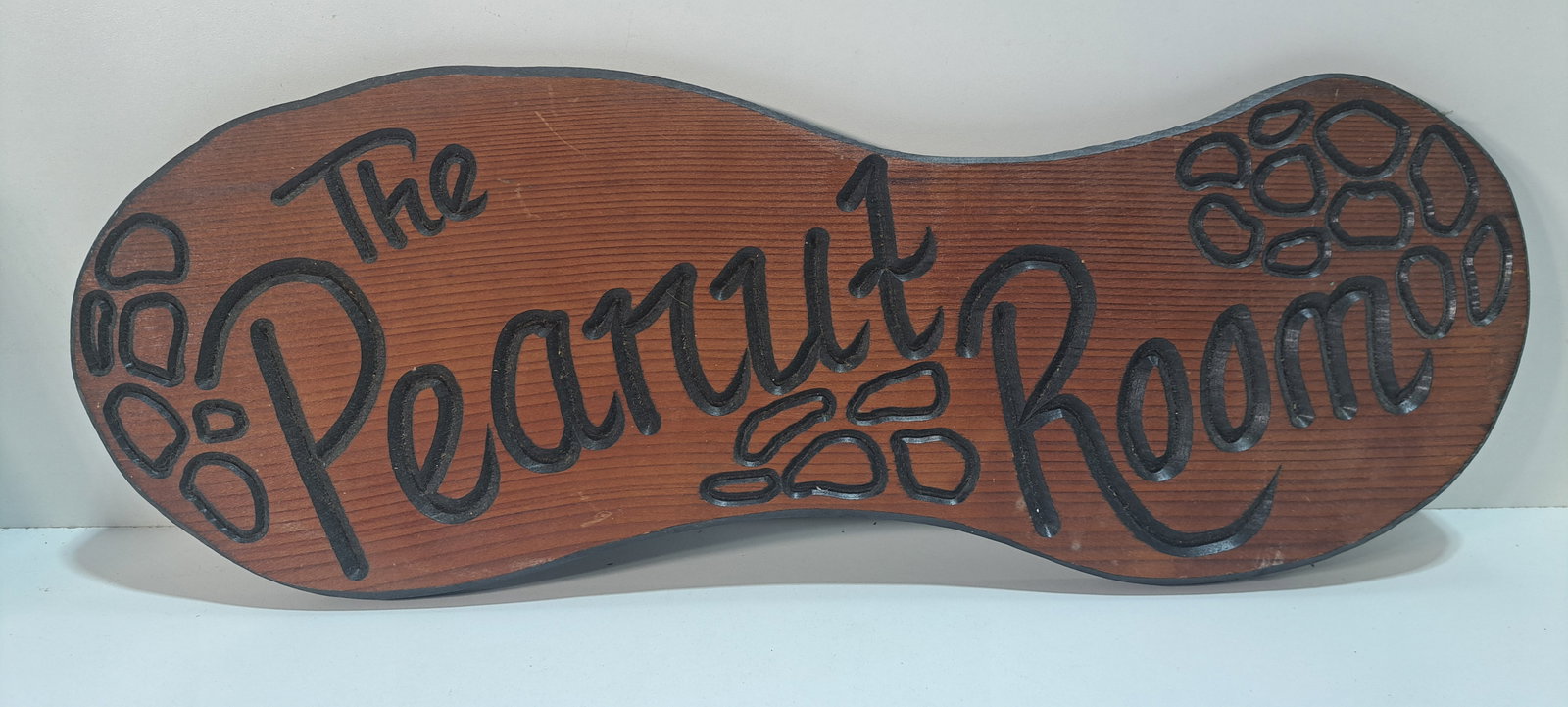 Peanut Room wooden sign: wooden sign, shaped like a peanut, engraved, The Peanut Room, minor wear, approx. 8.5" x 23.5", Please note: if picking up, location is different than auction location. Please contact us for options