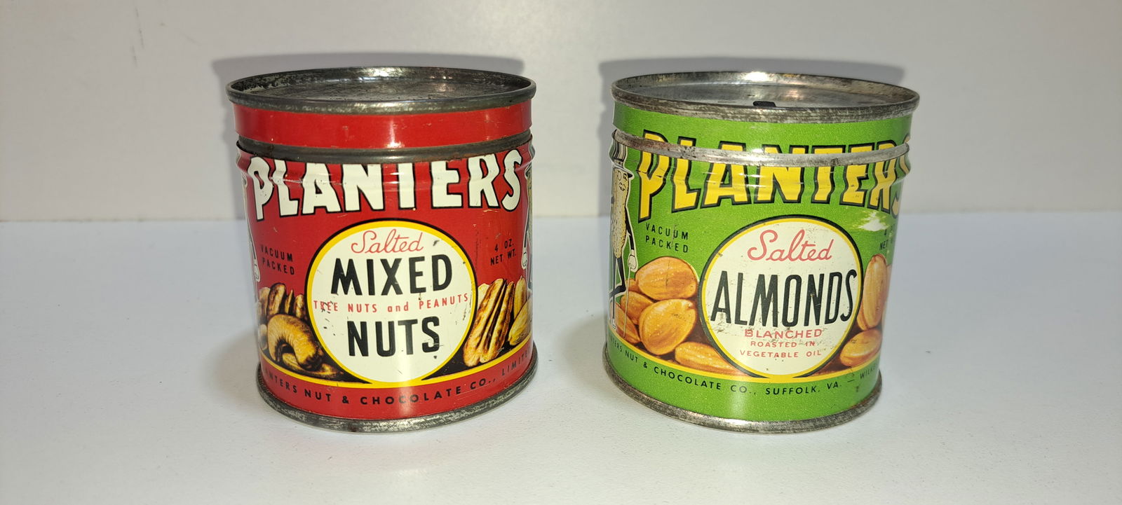 (2) Planters Peanuts 4 oz. tins: 2 Planters Peanuts 4 oz. tins, with lids, mixed nuts, salted almonds, opened and empty, each show minor wear, each approx. 2.75" tall, Please note: if picking up, location is different than auction lo