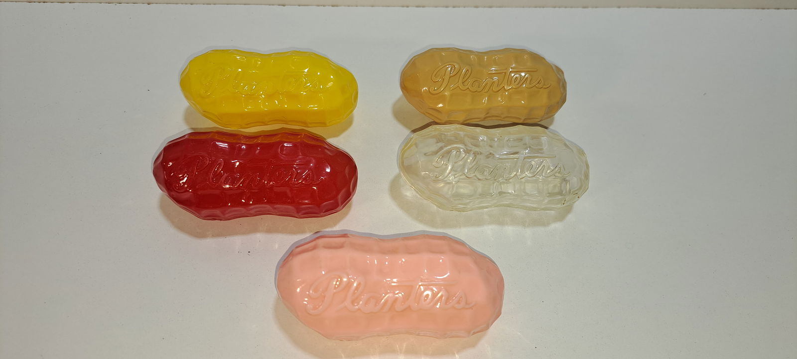 (5) Planters 2 piece peanuts: lot of 5 different colored, 2 piece plastic peanut containers, embossed "PLANTERS" in script lettering, also have Mr. Peanut embossed inside, yellow, red, tan, clear, pink, all in good condition,