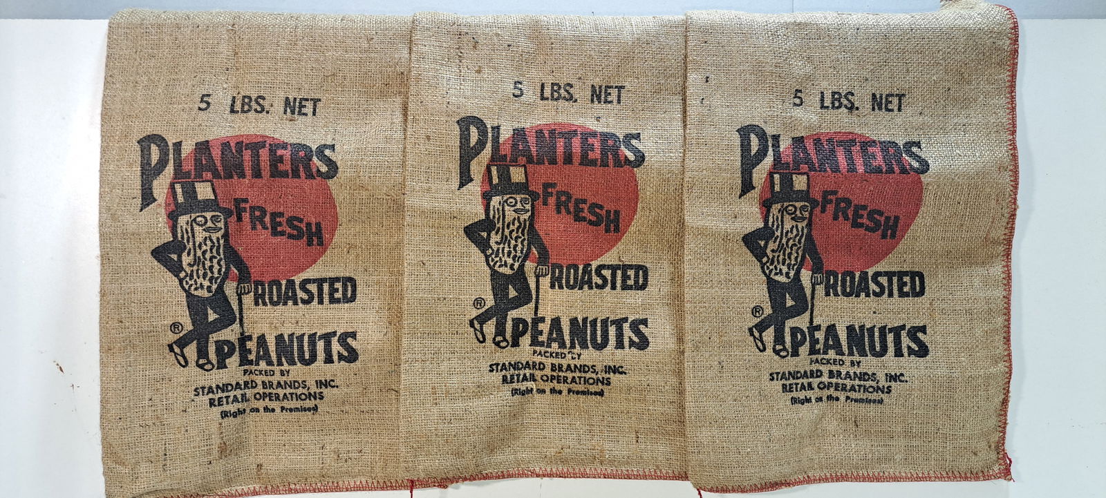 (5) Planters Peanuts burlap bags: lot of 5 Planters Peanuts burlap bags, 3-5 lb. bags, 2 different 1 lb. bags, all in good condition, Please note: if picking up, location is different than auction location. Please contact us for optio