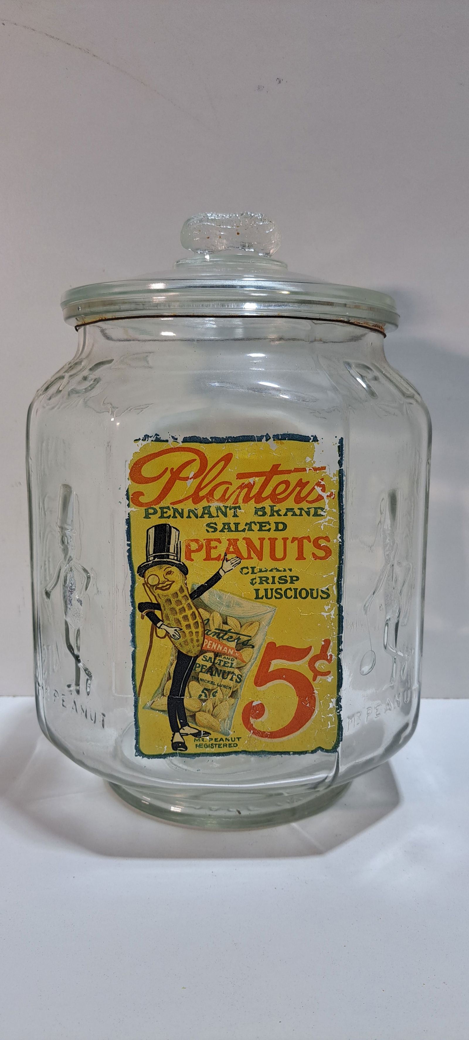 Planters Peanuts glass jar: Planters Peanuts, clear glass, counter top 8 sided jar, with label, correct lid with peanut shaped handle, Made In USA, original, not a reproduction, heavily embossed, label has wear as shown, no chip