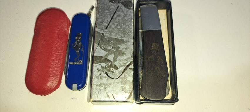 (2) Mr. Peanut pocket knives: 2 Mr. Peanut pocket knives, one with wooden handle, single blade, in box, approx. 2.75" long, other is siss army style, in red sheath, approx. 2.25" long, both in excellent, unused condition, Please n