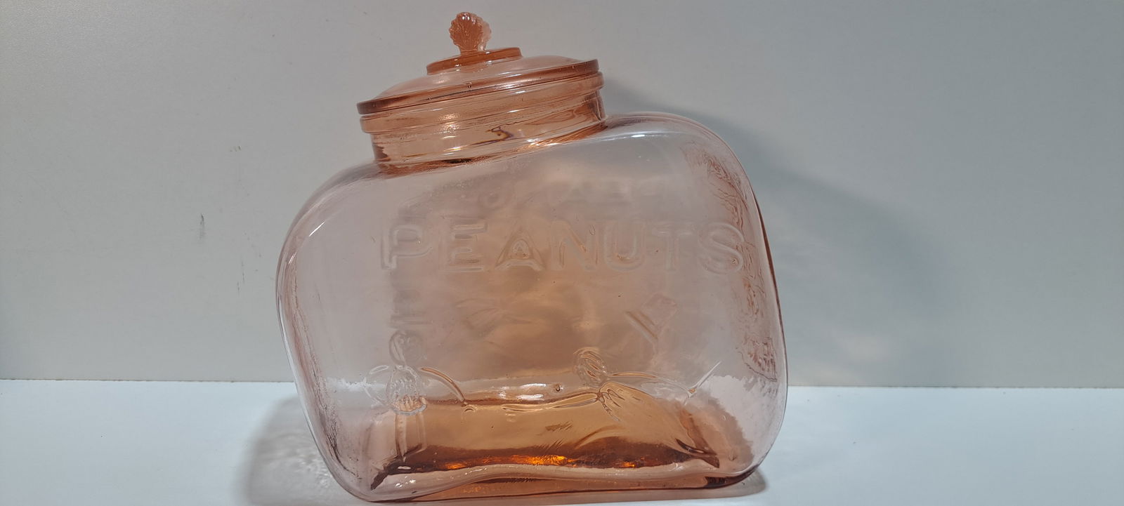 peanut jar: slanted, pink, glass peanut jar, lid has peanut shaped handle, embossed with images of Mr. Peanut, this is a fantasy jar, not original very good condition, no chips or cracks, approx. 5.25" x 10" x 9.