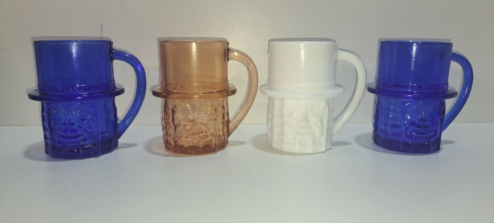 (4) Mr. Peanut glass mugs: lot of 4 Mr. Peanut glass mugs with handles, 2- blue, 1- pink, 1- white, these are fantasy mugs, all in good condition, each approx. 3.75" tall, Please note: if picking up, location is different than