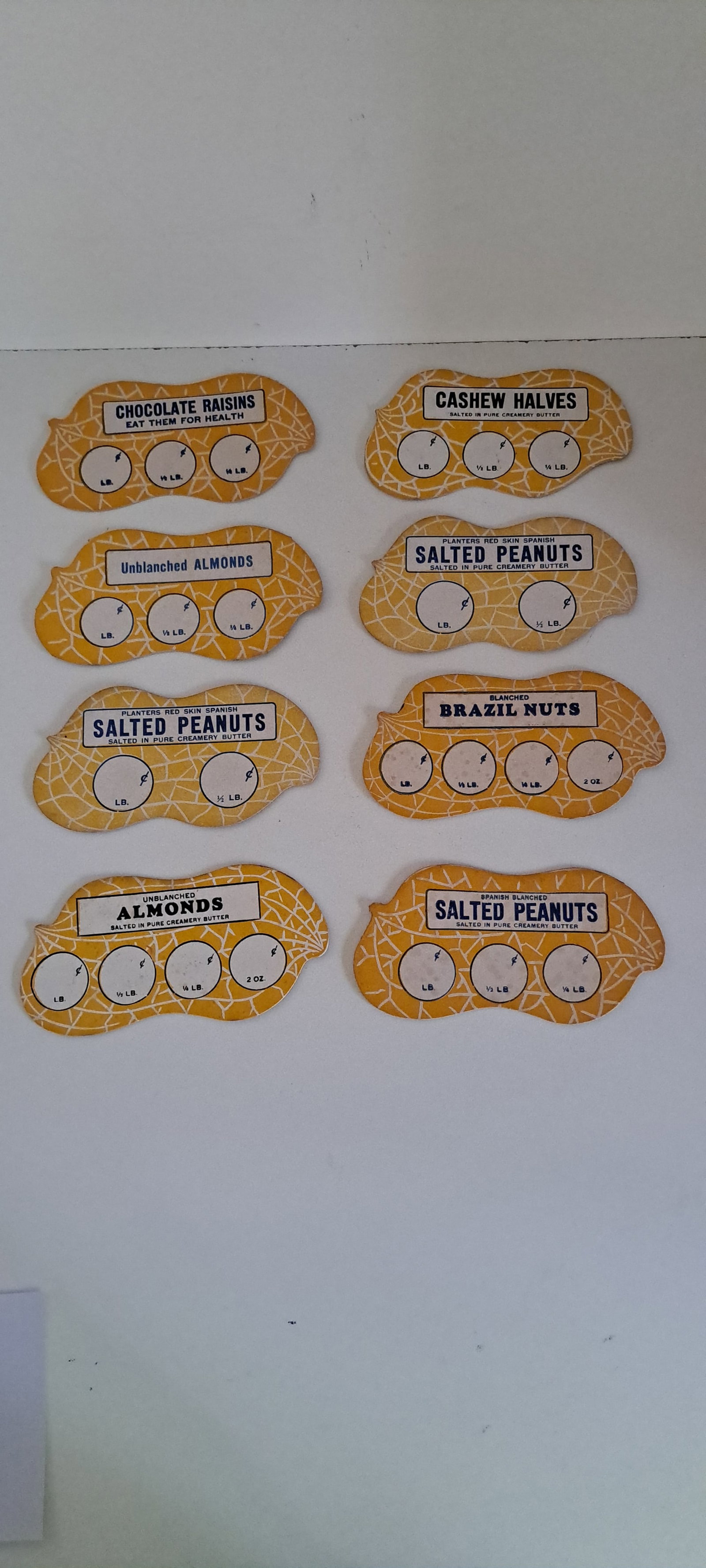 (8) Planters Peanuts pricer cards: Lot of 8 different, cardboard, peanut shaped, pricer cards for various kinds of nuts, used in the Planters Peanuts stores. All appear unused. Each approx. 3"x 6". pamphlet. Appears unused, very good