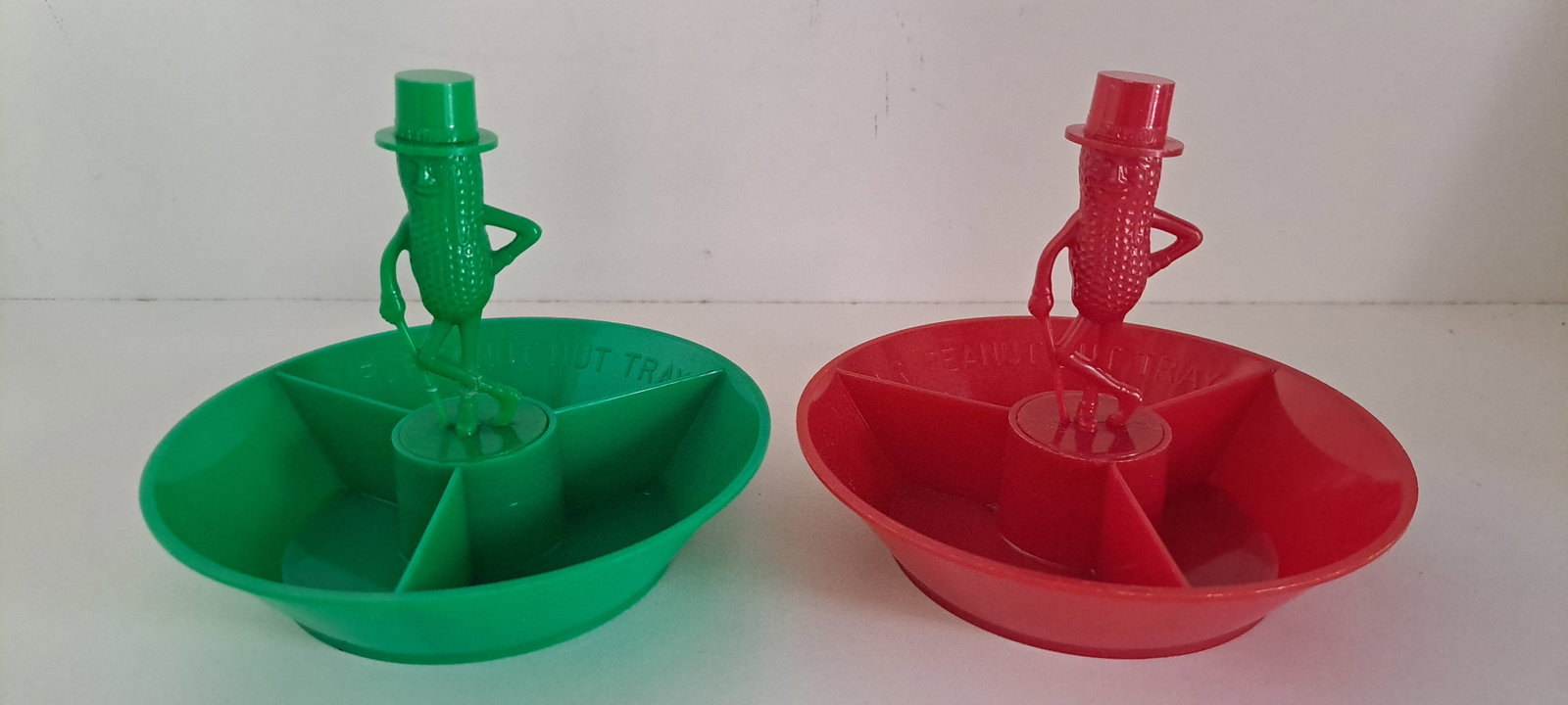 (2) Mr. Peanut 3 compartment nut dishes: 1- red, 1- green, Plastic 3 compartment nut dishes. With figural Mr. Peanut in center. Both in very good condition. Each approx. 4.5" tall. Please see our shipping policy for options.