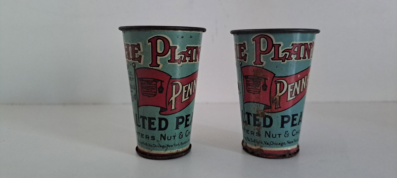 (2) Planters Peanuts tin measuring scoops: 2 versions of Planters Peanuts tin measuring scoops. Slightly different graphics. Each show wear. Each approx. 2.75" tall. Please see our shipping policy for options.
