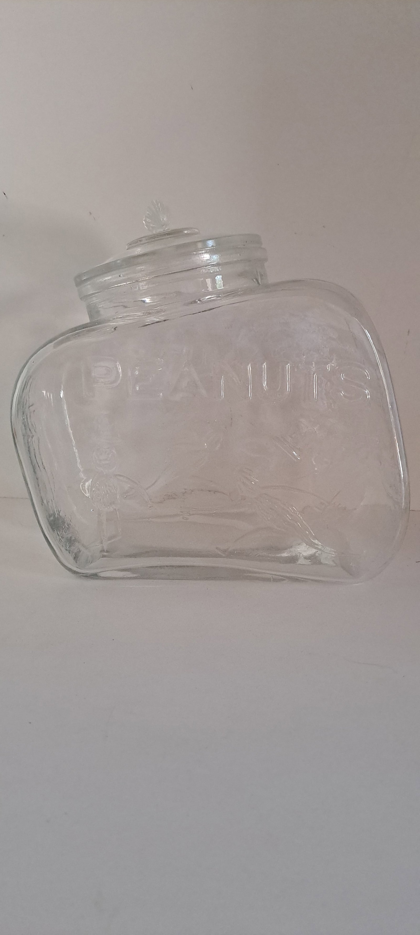 Glass peanut jar: Clear glass, slanted, counter jar. Embossed, with running Mr. Peanuts. Peanut shaped handle on lid. This is a fantasy jar, not original. Very good condition. no chips or cracks. Please see our