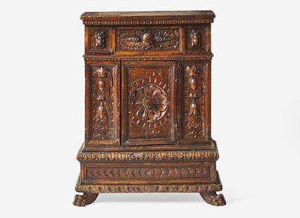 An Italian Renaissance carved walnut cabinet, 16th / 17th century Of slim depth, with rectangular: An Italian Renaissance carved walnut cabinet, 16th / 17th century Of slim depth, with rectangular top, with single drawer above single door revealing two shelves, both flanked by carved panels with ma