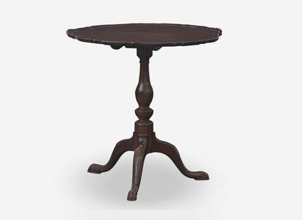 A George III carved mahogany tilt-top tea table, circa 1760 With scalloped pie-crust top, on split: A George III carved mahogany tilt-top tea table, circa 1760 With scalloped pie-crust top, on split baluster support, on three cabriole legs with foliate carved knees, ball-and-claw feet. H: 28 &